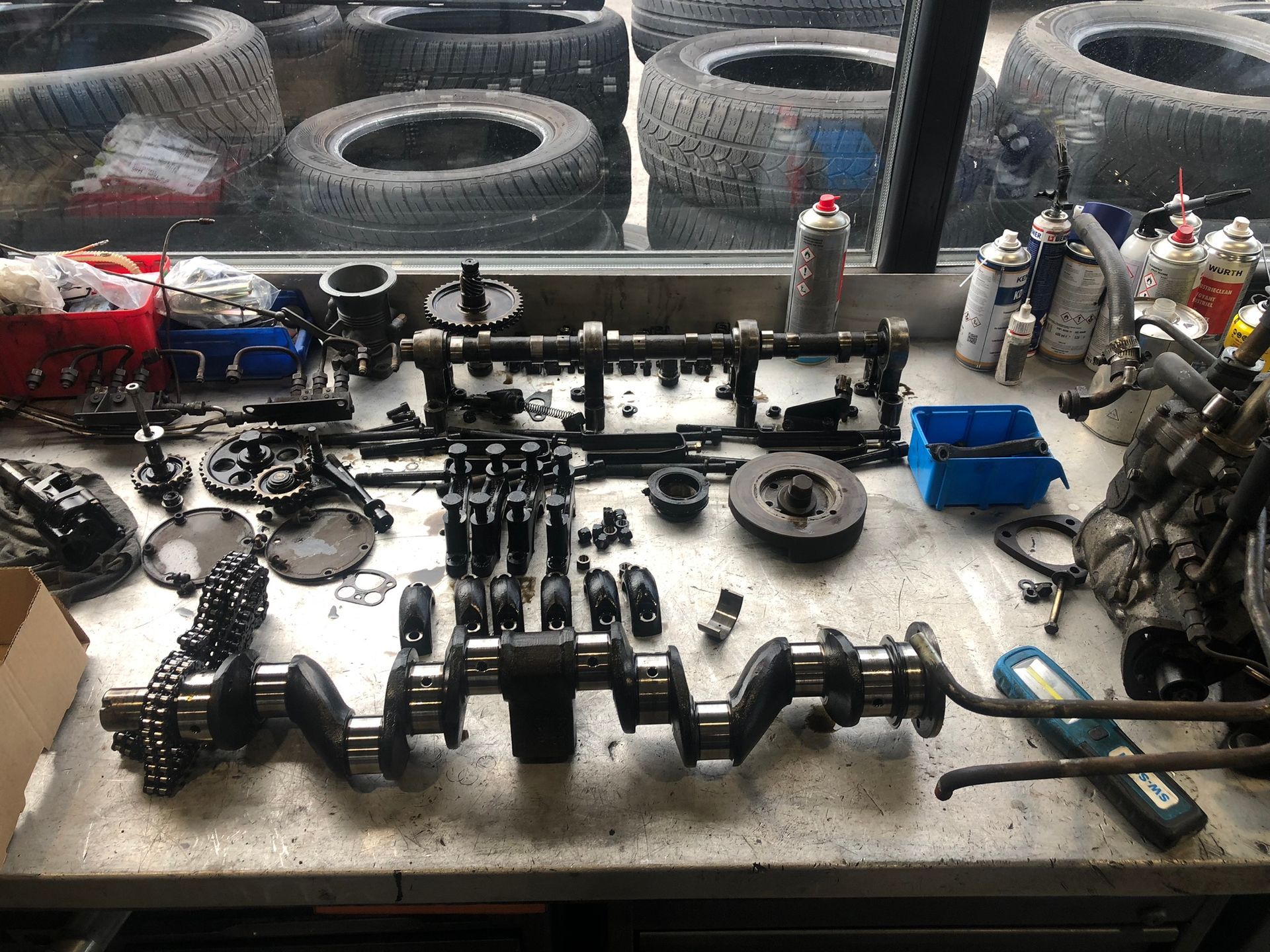 Un tas de pièces sont posées sur une table dans un garage.