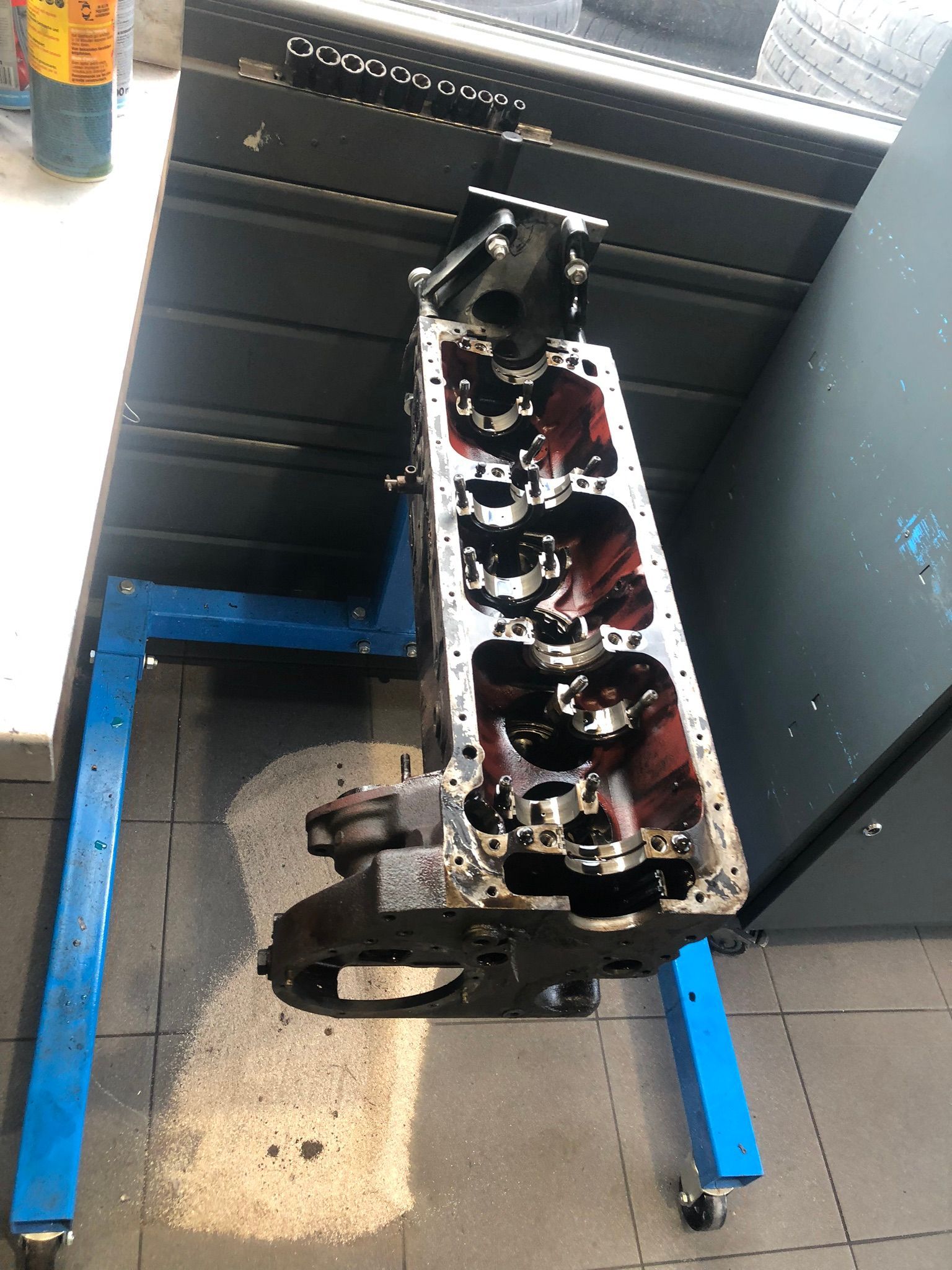 Un bloc moteur de voiture est posé sur un support bleu.