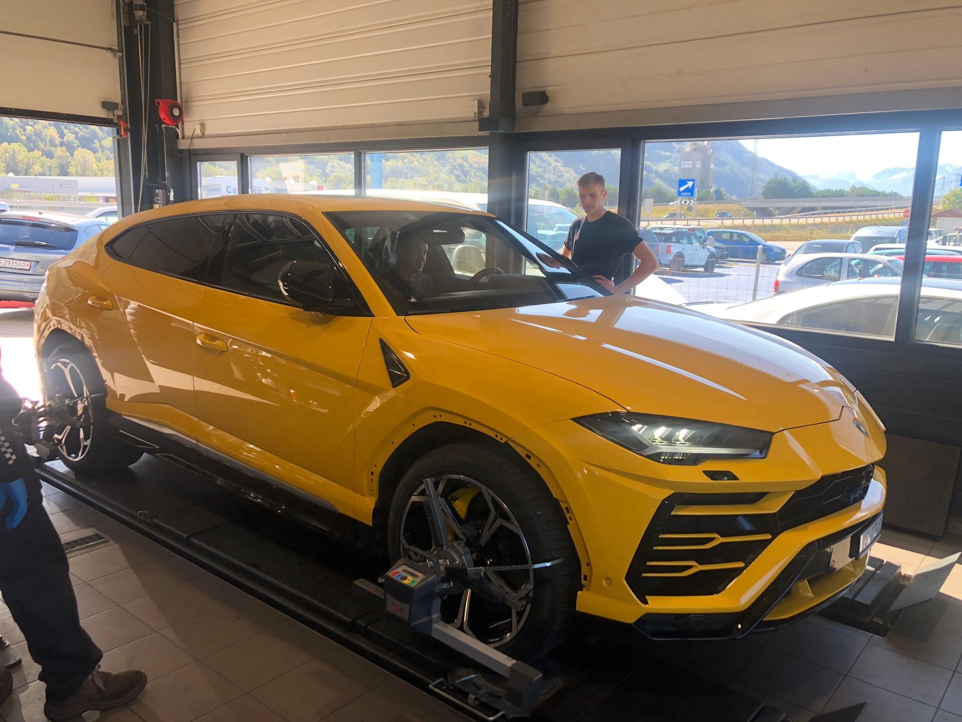 Un homme se tient à côté d’une voiture jaune dans un garage.