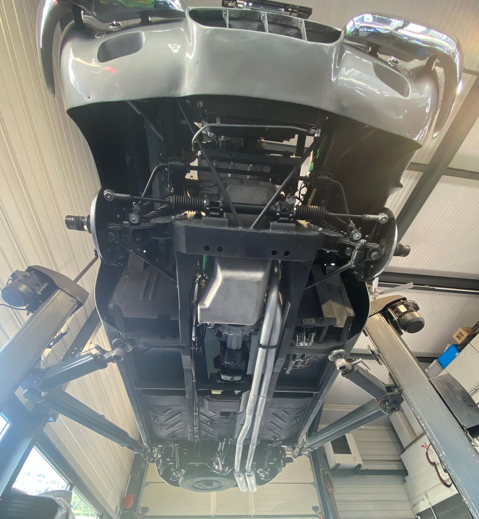 Le dessous d'une voiture est montré dans un garage.