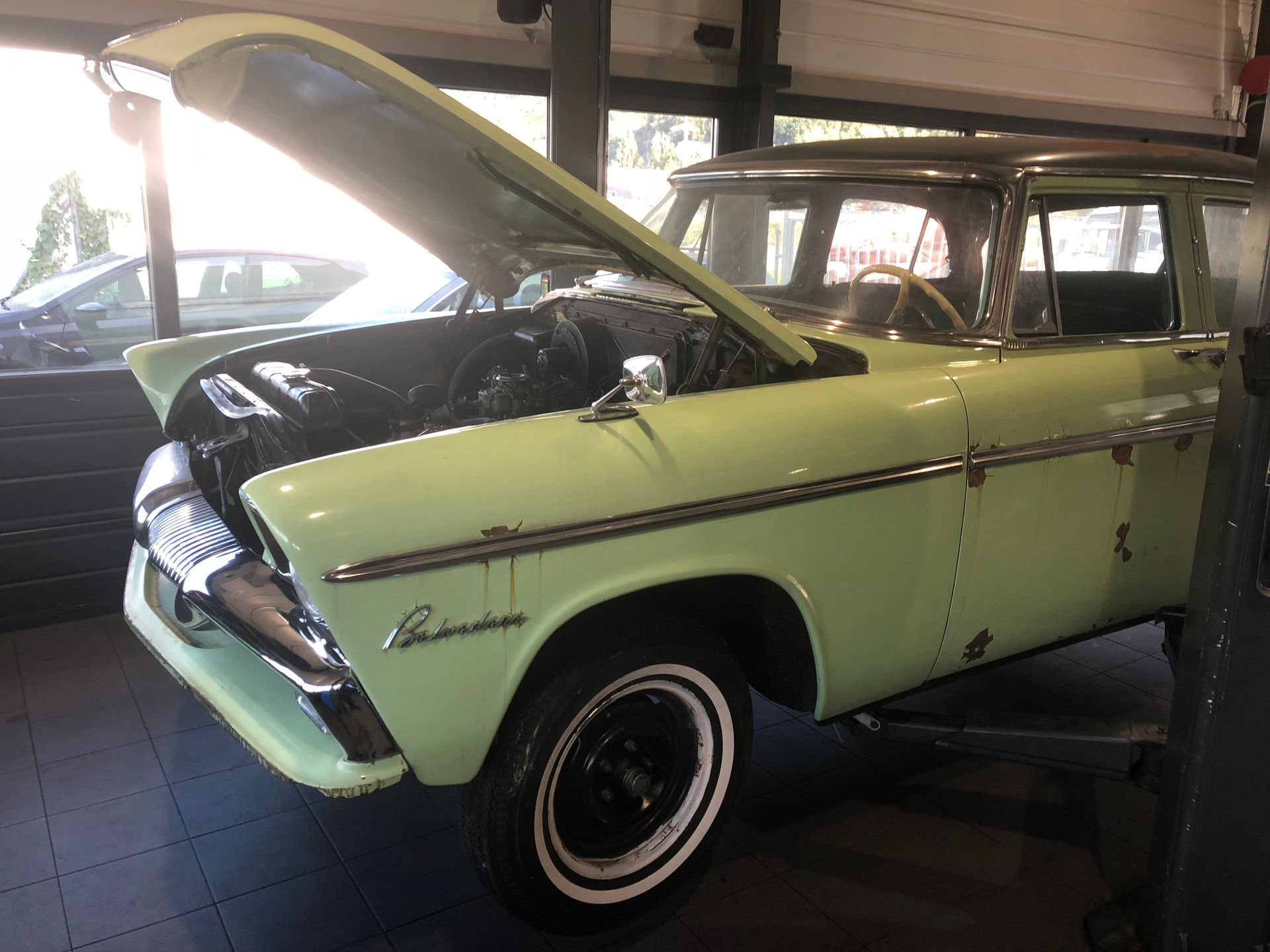 Une voiture verte avec le capot relevé dans un garage