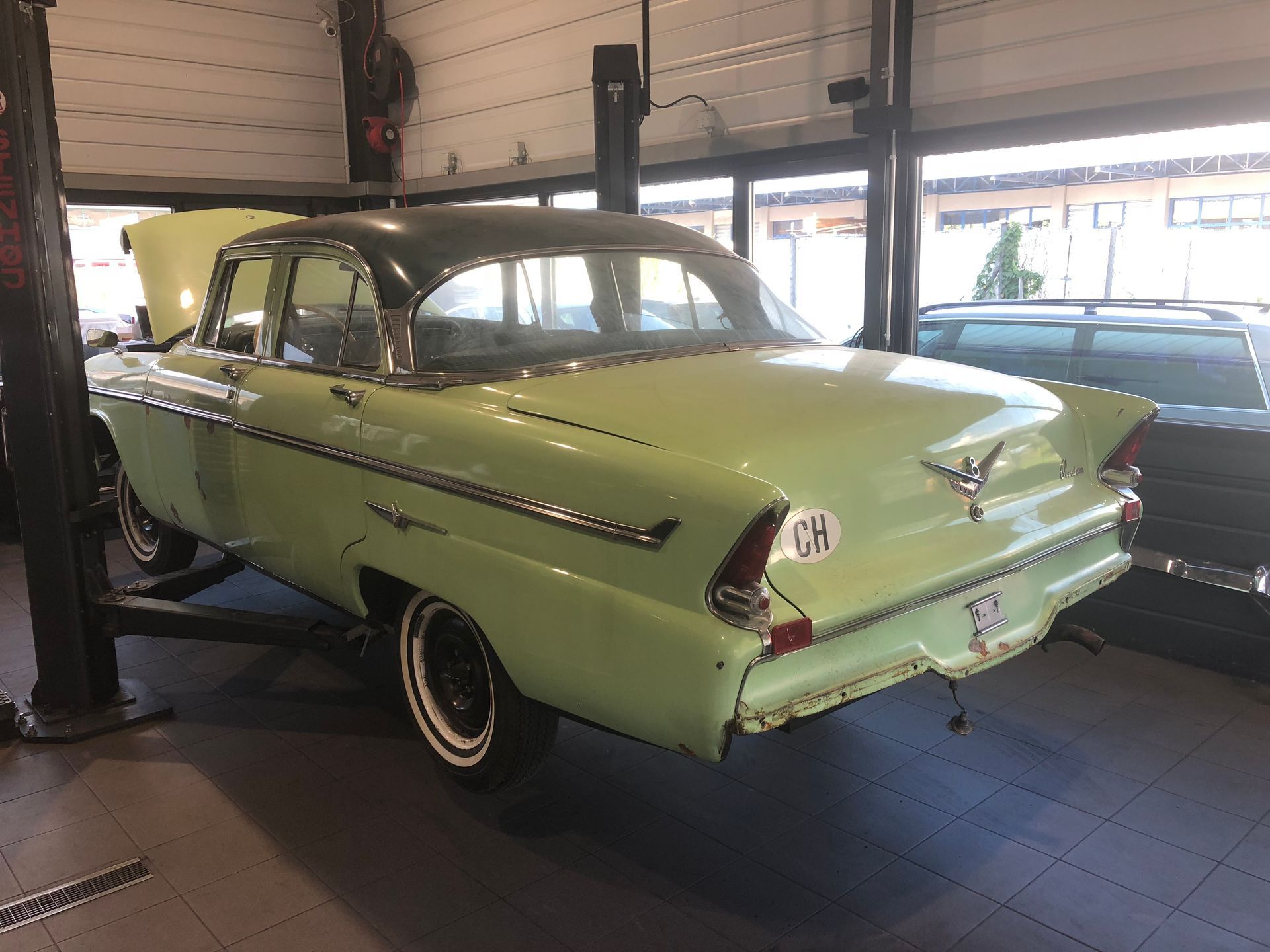 Une voiture verte est assise sur un ascenseur dans un garage.