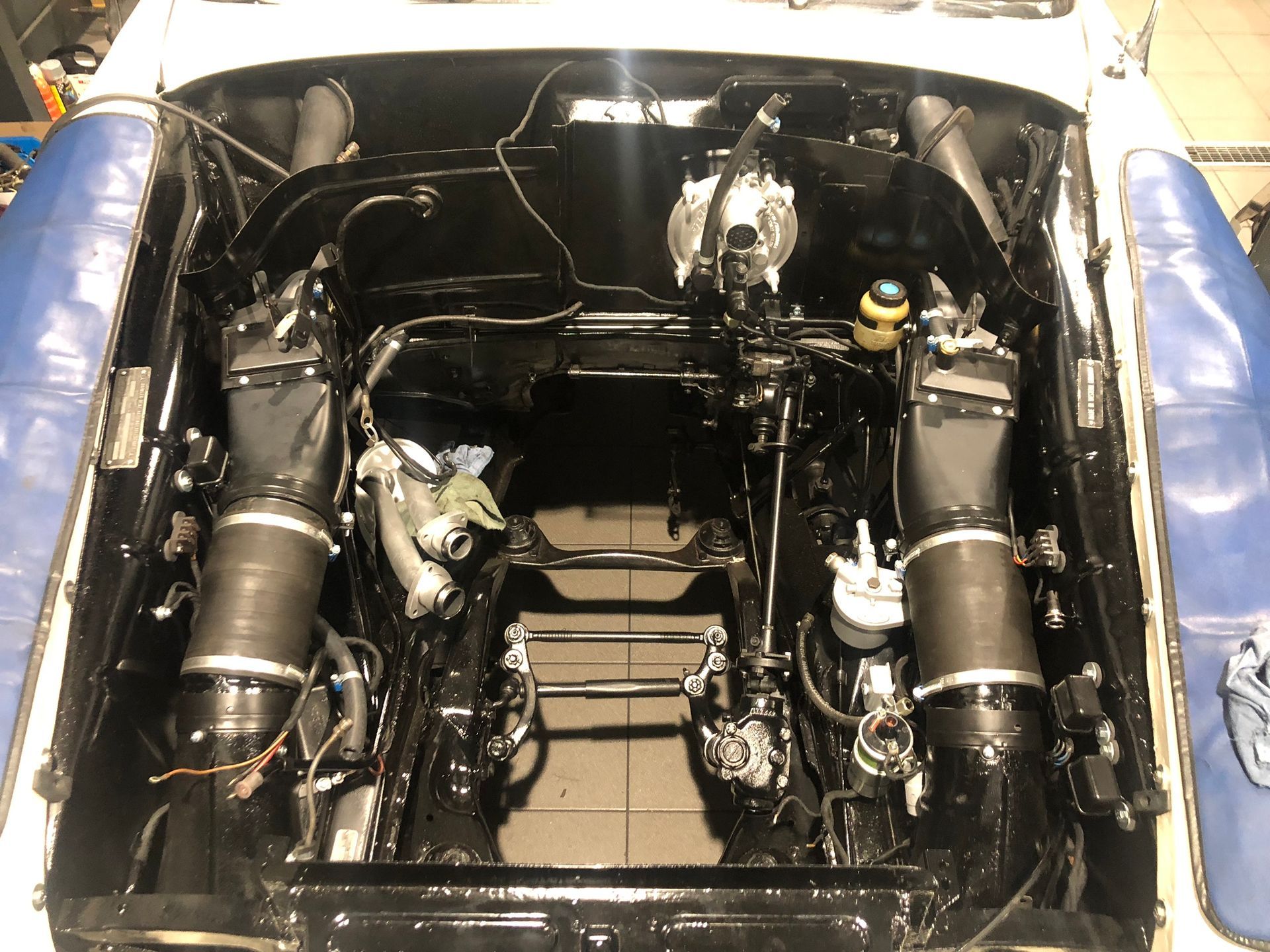 Le capot d'une voiture est ouvert et le moteur est visible.