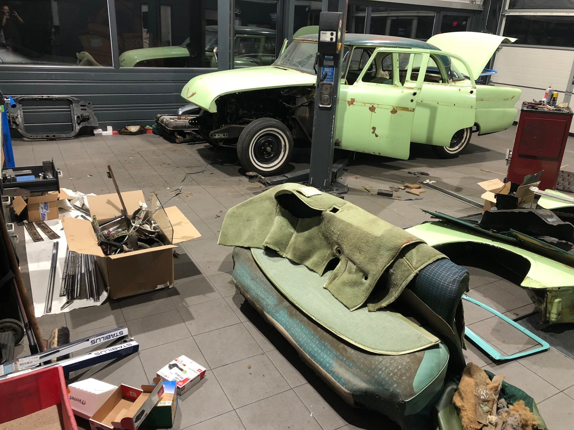 Une voiture verte est assise sur un ascenseur dans un garage.