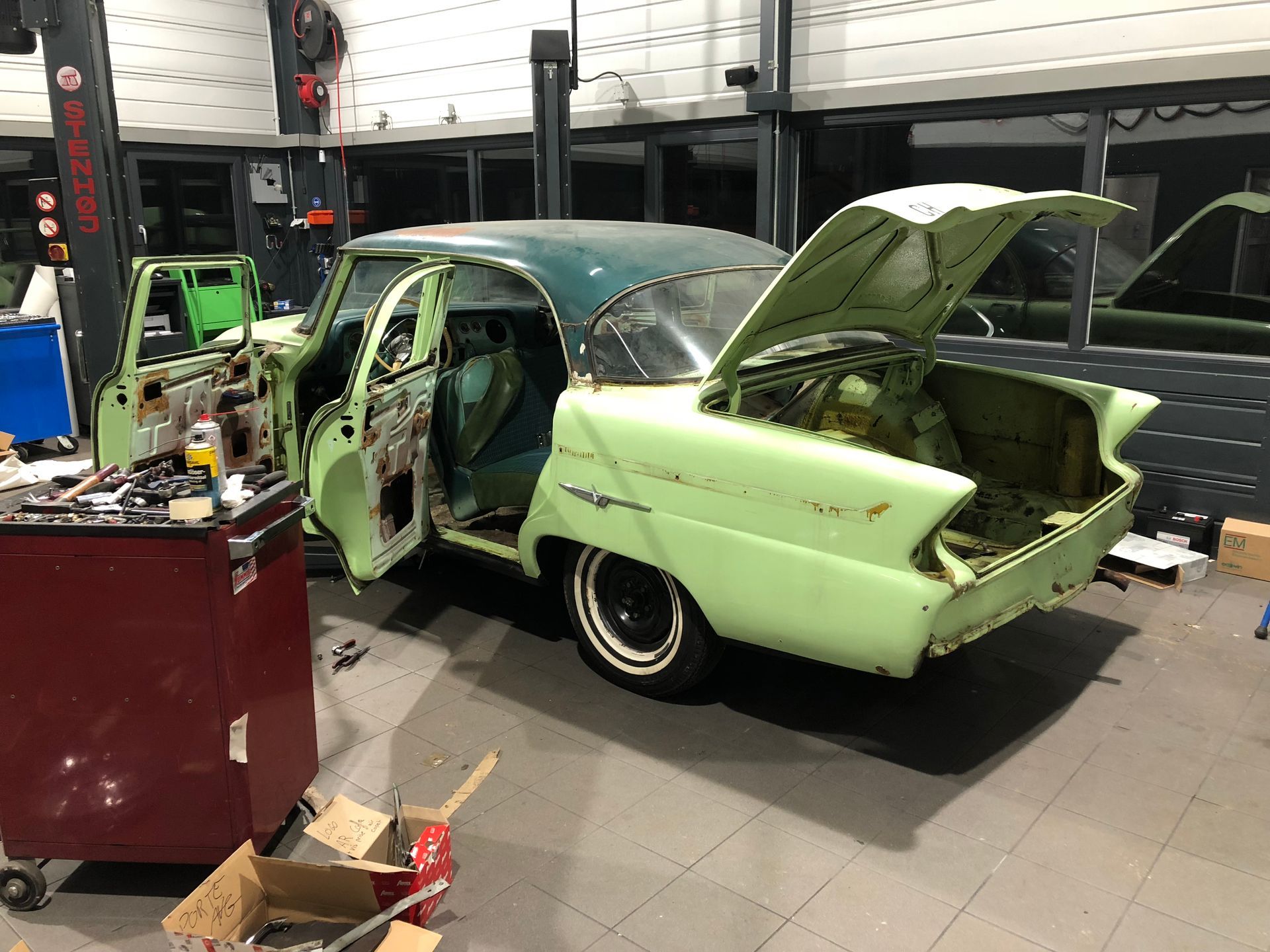 Une voiture verte est assise dans un garage avec son coffre ouvert.