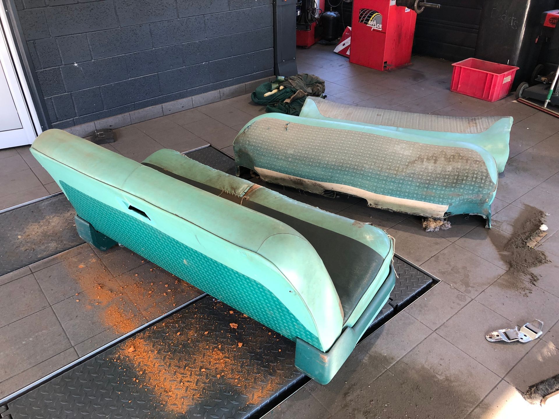 Un canapé vert est posé sur un sol carrelé dans un garage.