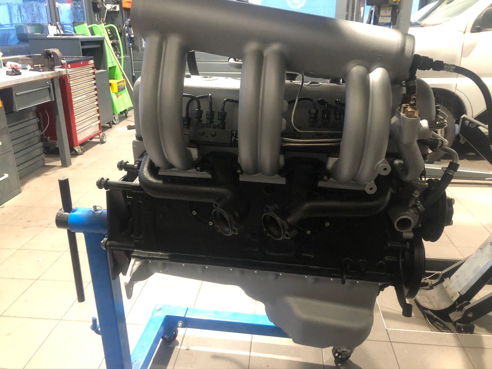 Un moteur de voiture est posé sur un support dans un garage.