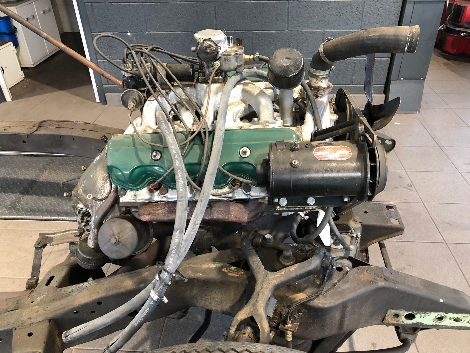 Un moteur de voiture est posé sur un châssis dans un garage.