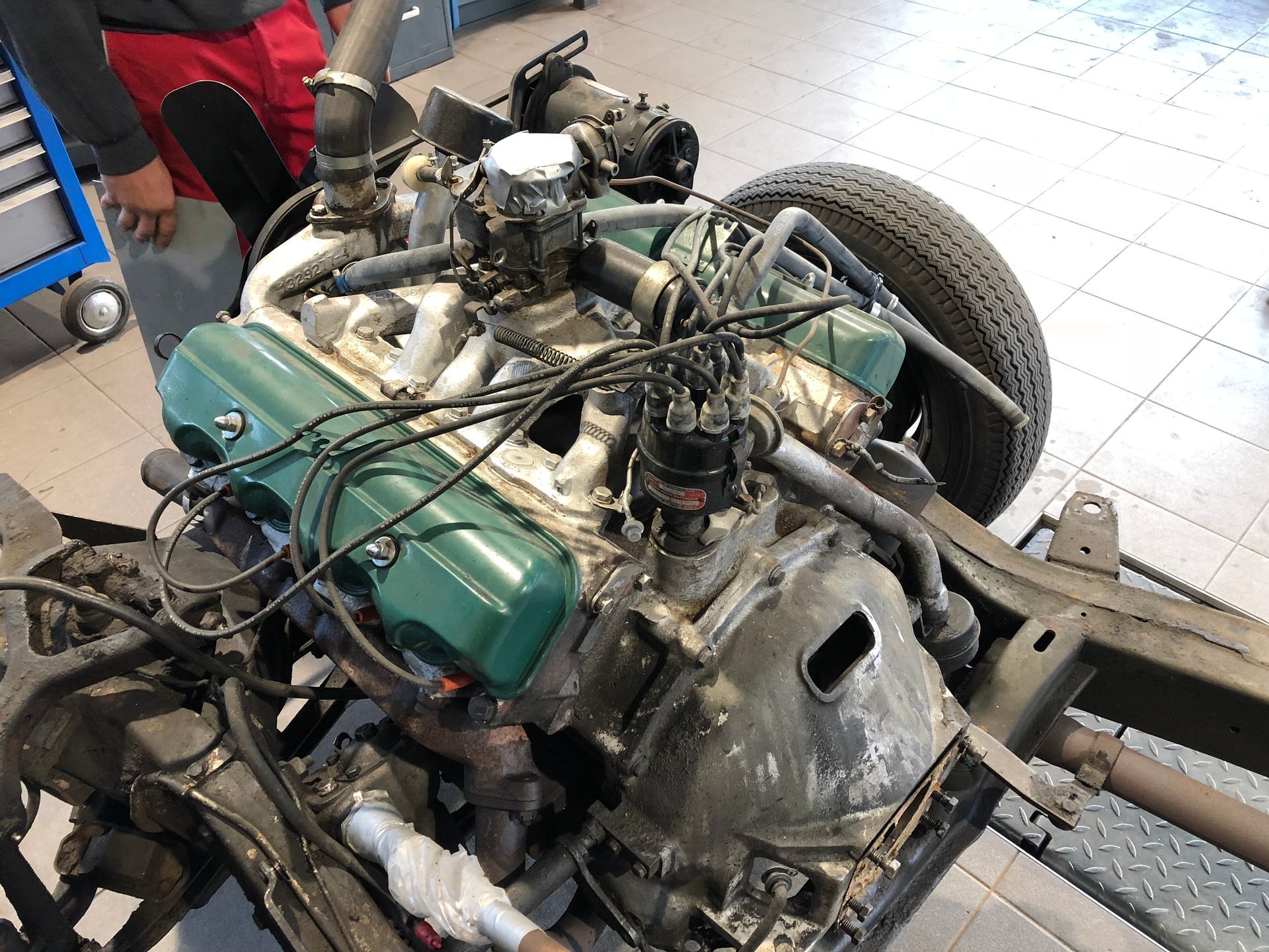 Un homme travaille sur un moteur de voiture dans un garage.