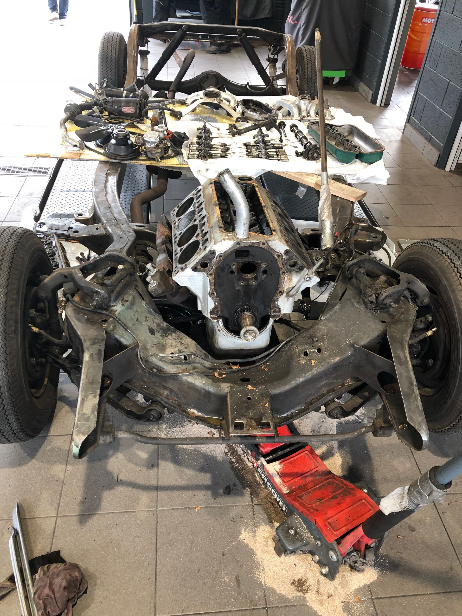 Une voiture est démontée dans un garage avec un cric.