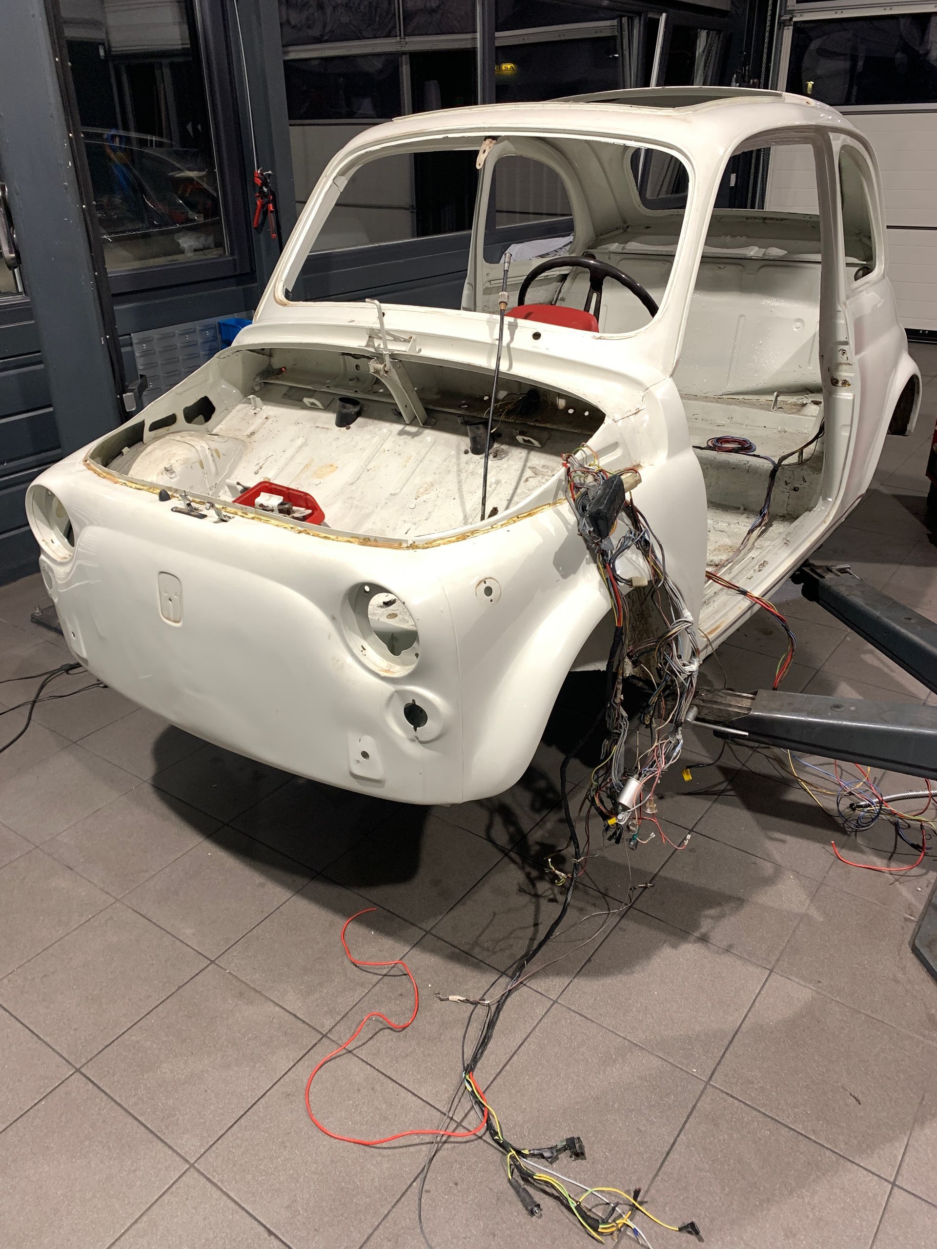 Une voiture blanche est posée sur un sol carrelé dans un garage.