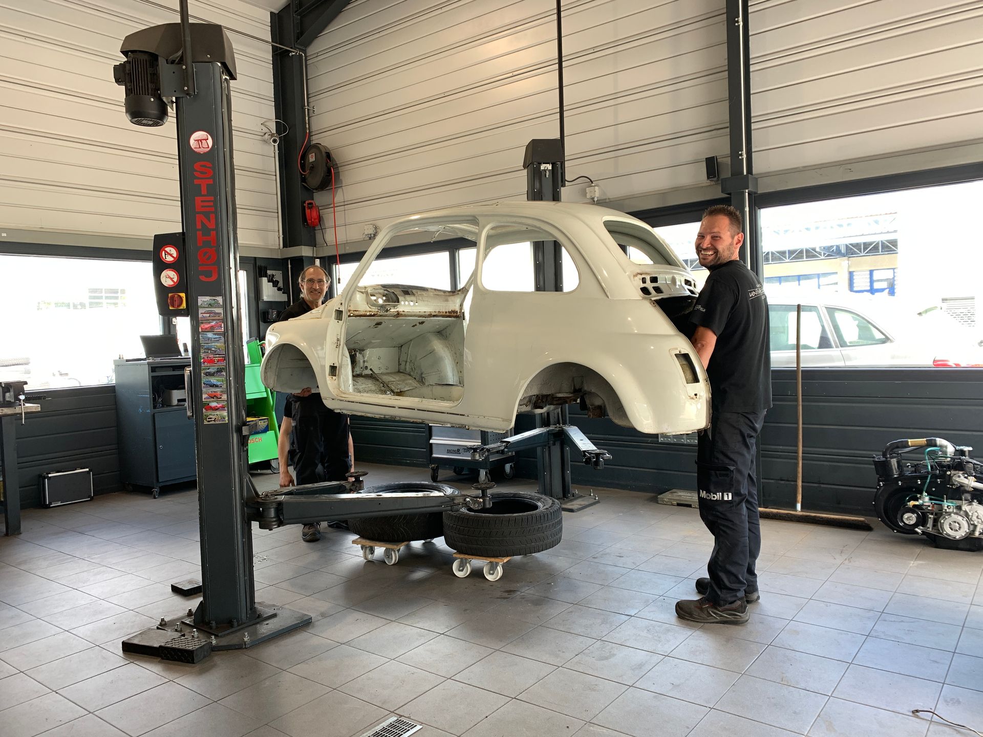 Un homme travaille sur une voiture sur un ascenseur dans un garage.
