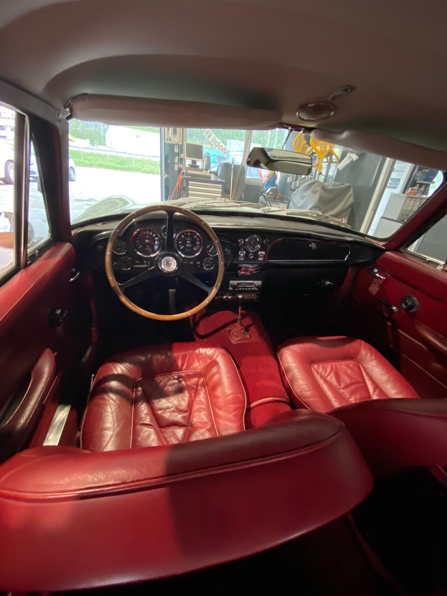 L'intérieur d'une voiture avec des sièges en cuir rouge et un volant en bois.