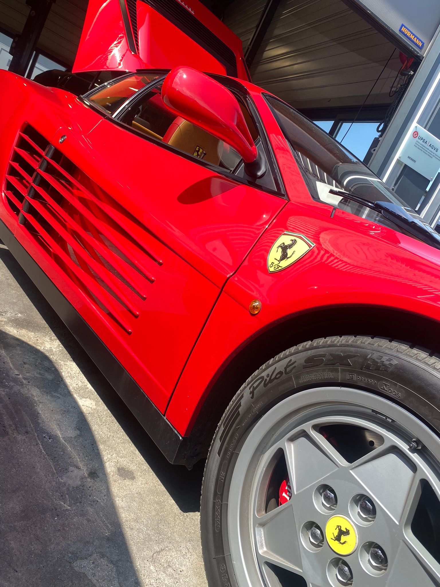 Une Ferrari rouge est garée devant une station-service