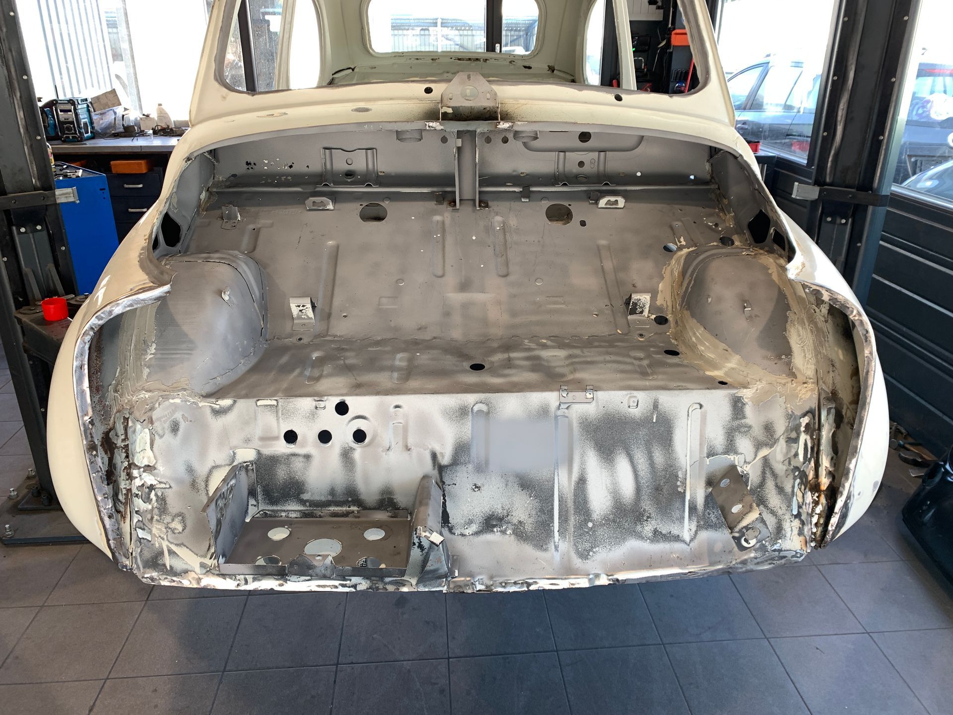 Une voiture blanche est assise sur un ascenseur dans un garage.