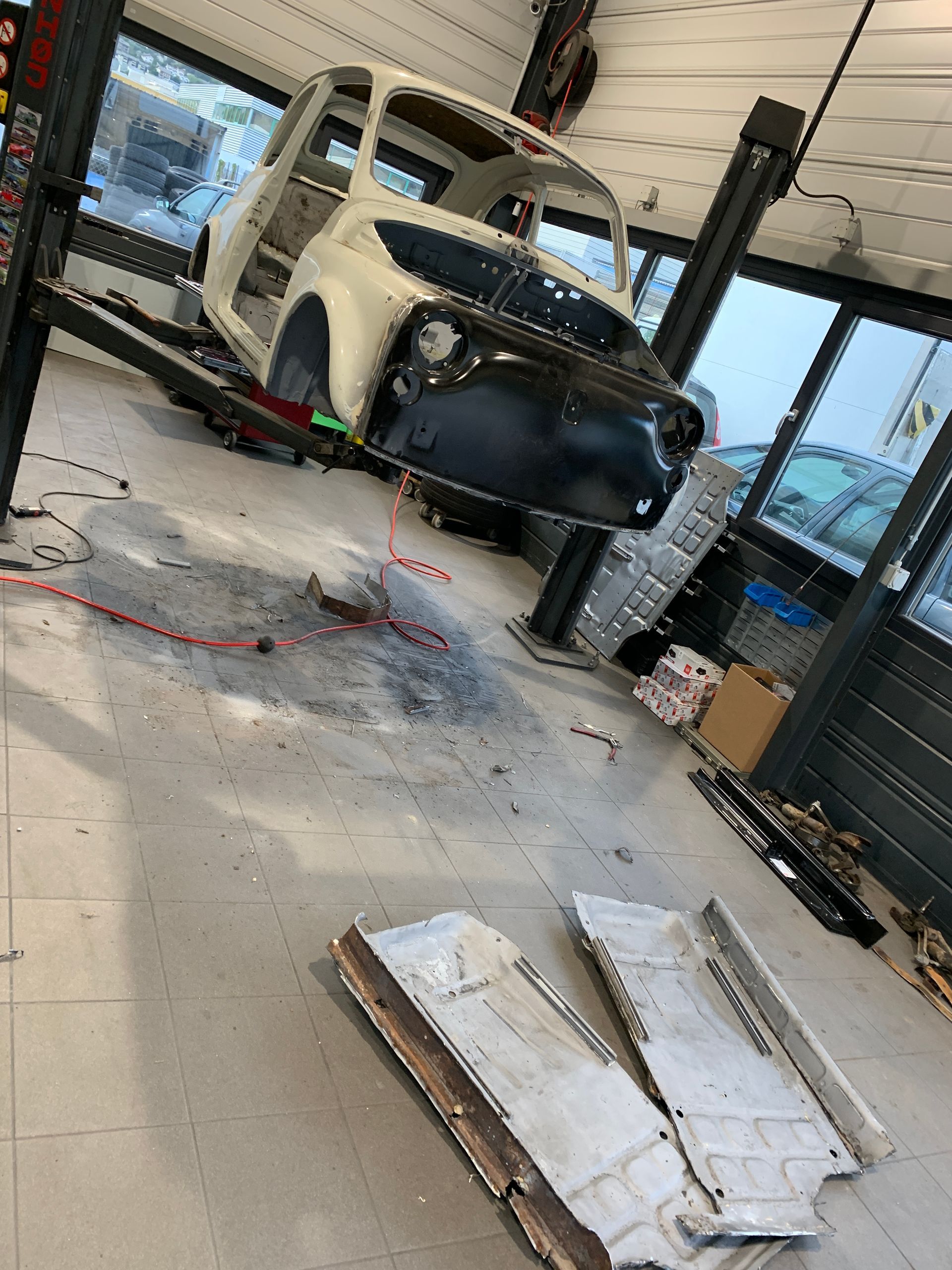 Une voiture blanche est assise sur un ascenseur dans un garage.