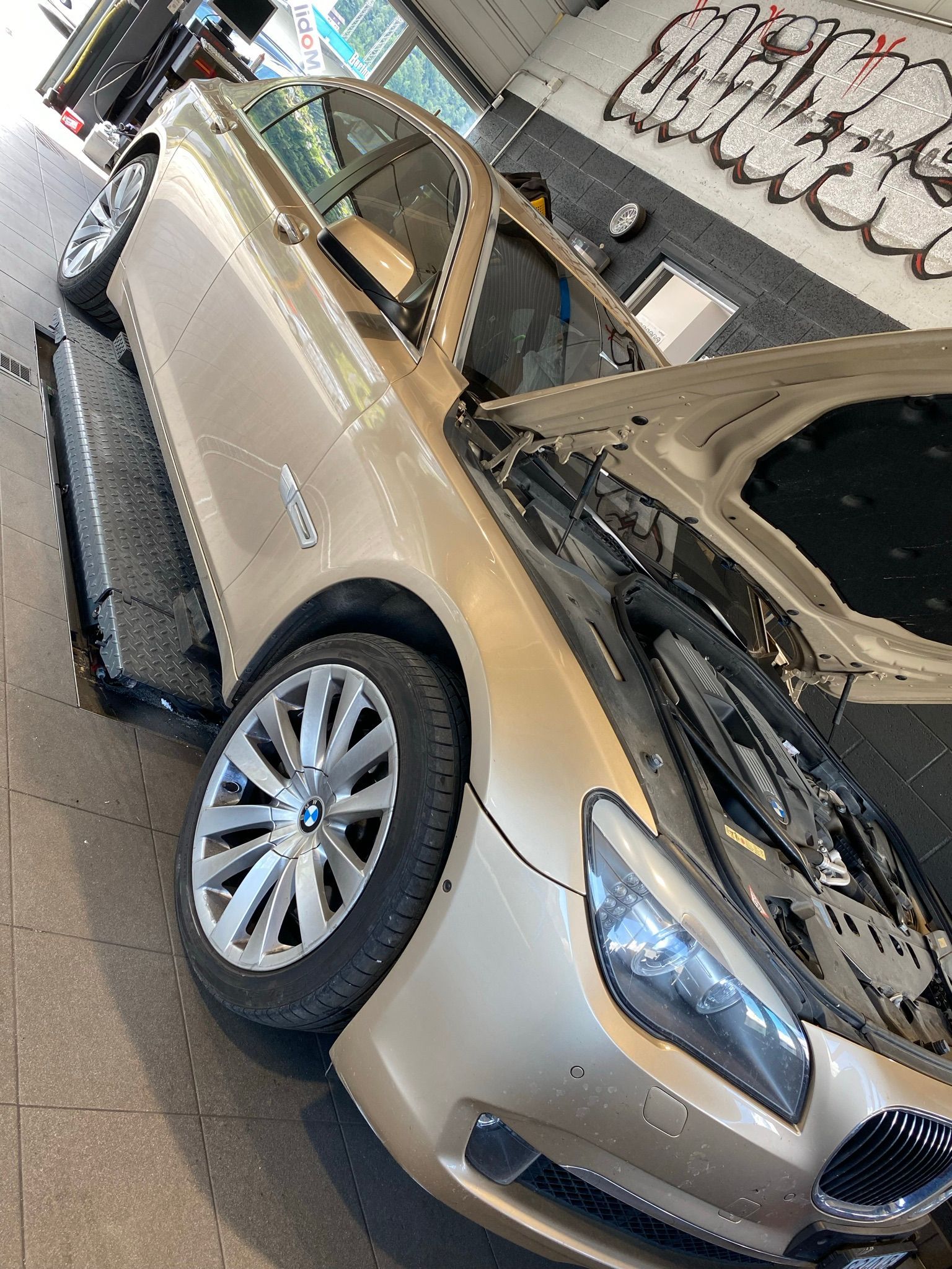 Une voiture avec le capot relevé est garée dans un garage.