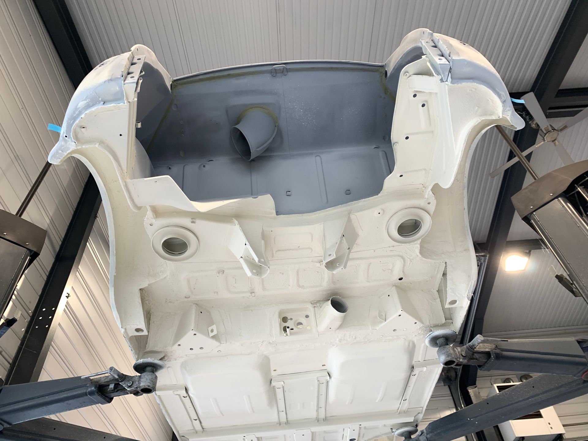 Une voiture blanche est assise sur un ascenseur dans un garage.