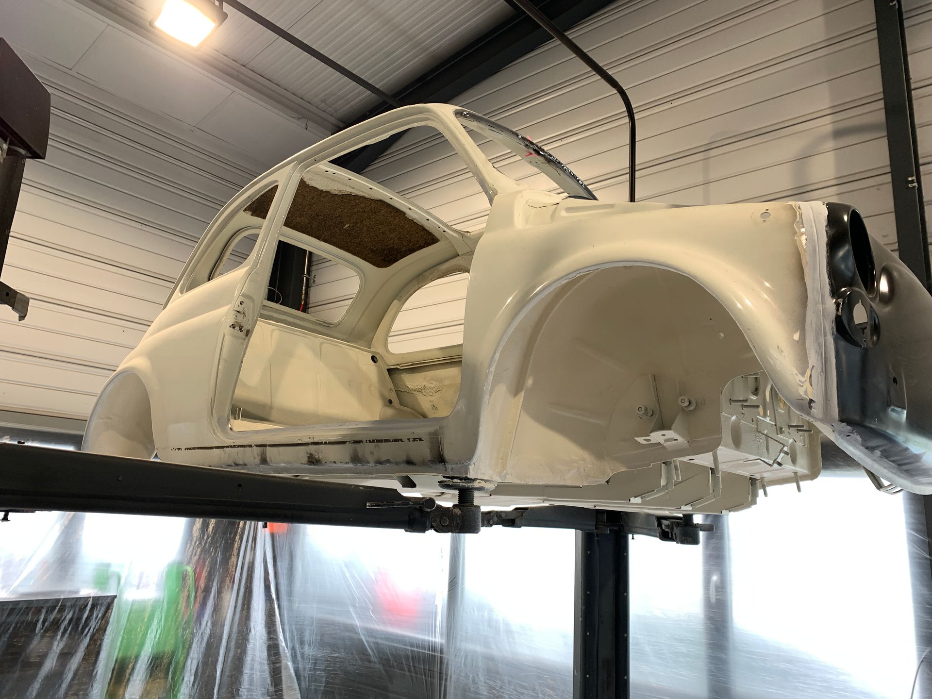 Une voiture blanche est assise sur un ascenseur dans un garage.