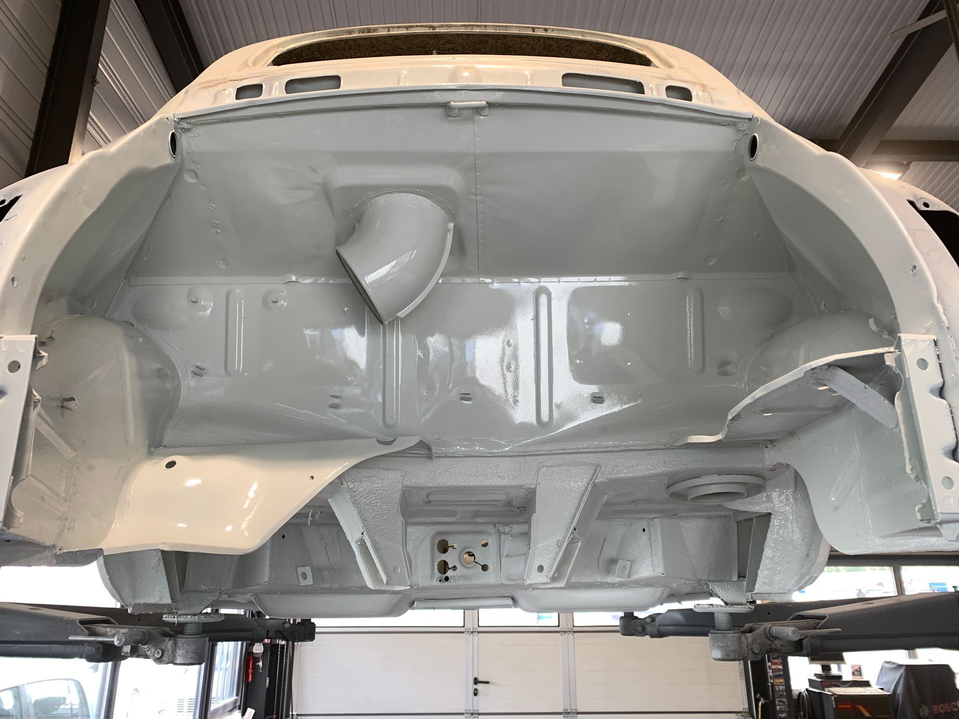 Une voiture blanche est assise sur un ascenseur dans un garage.