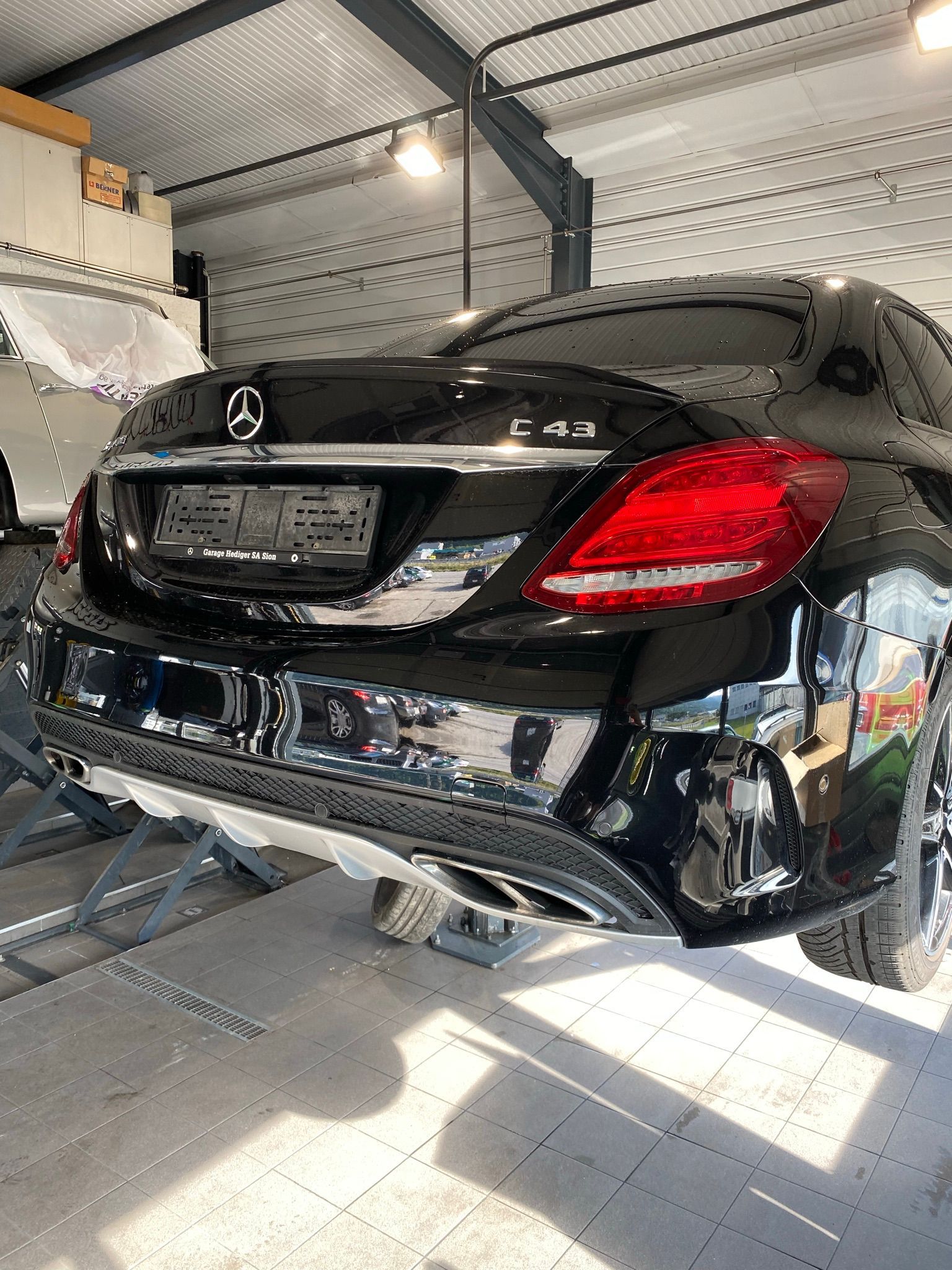 Une Mercedes Benz noire est assise sur un ascenseur dans un garage.