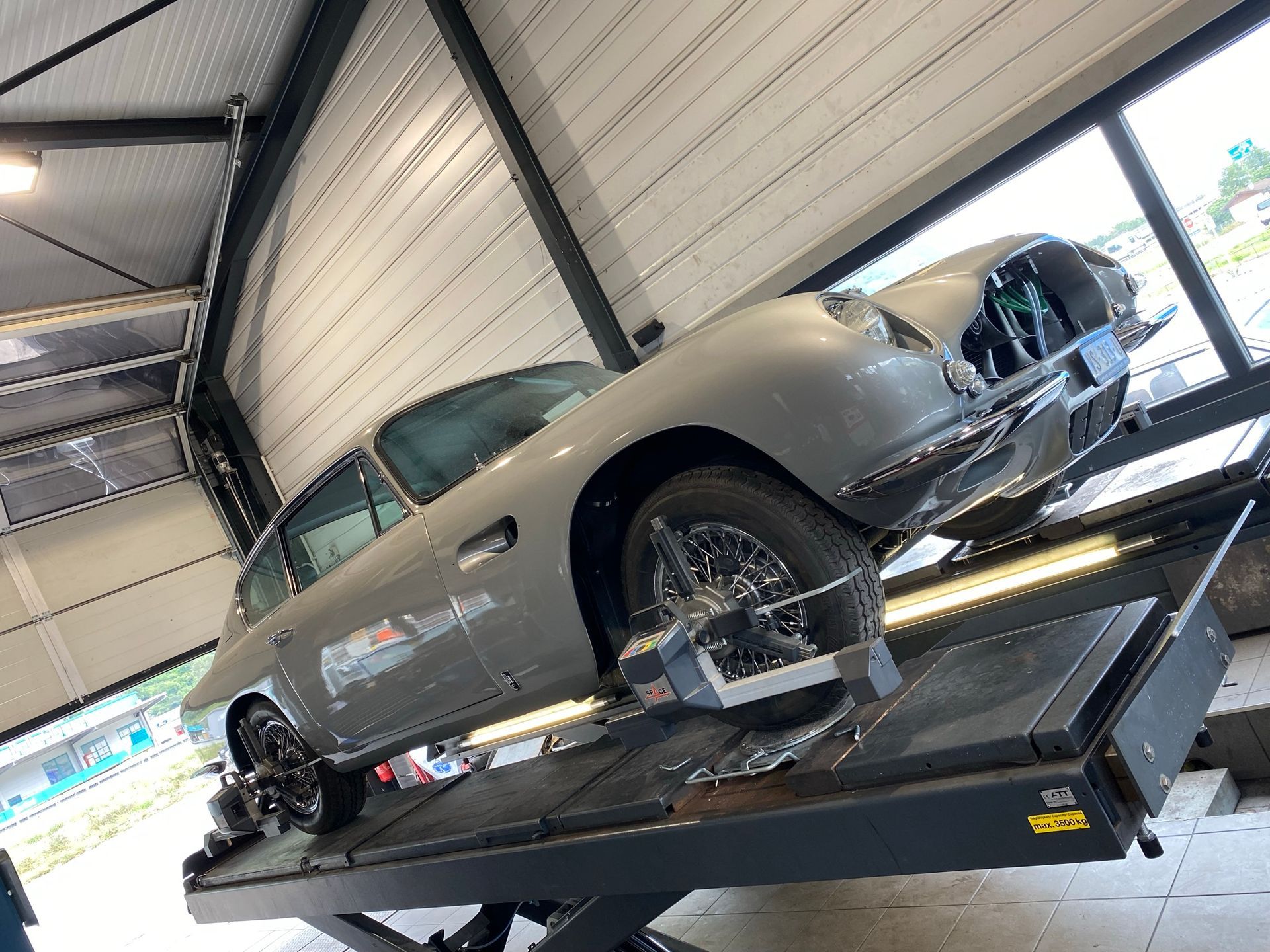 Une voiture est posée au sommet d’un ascenseur dans un garage.