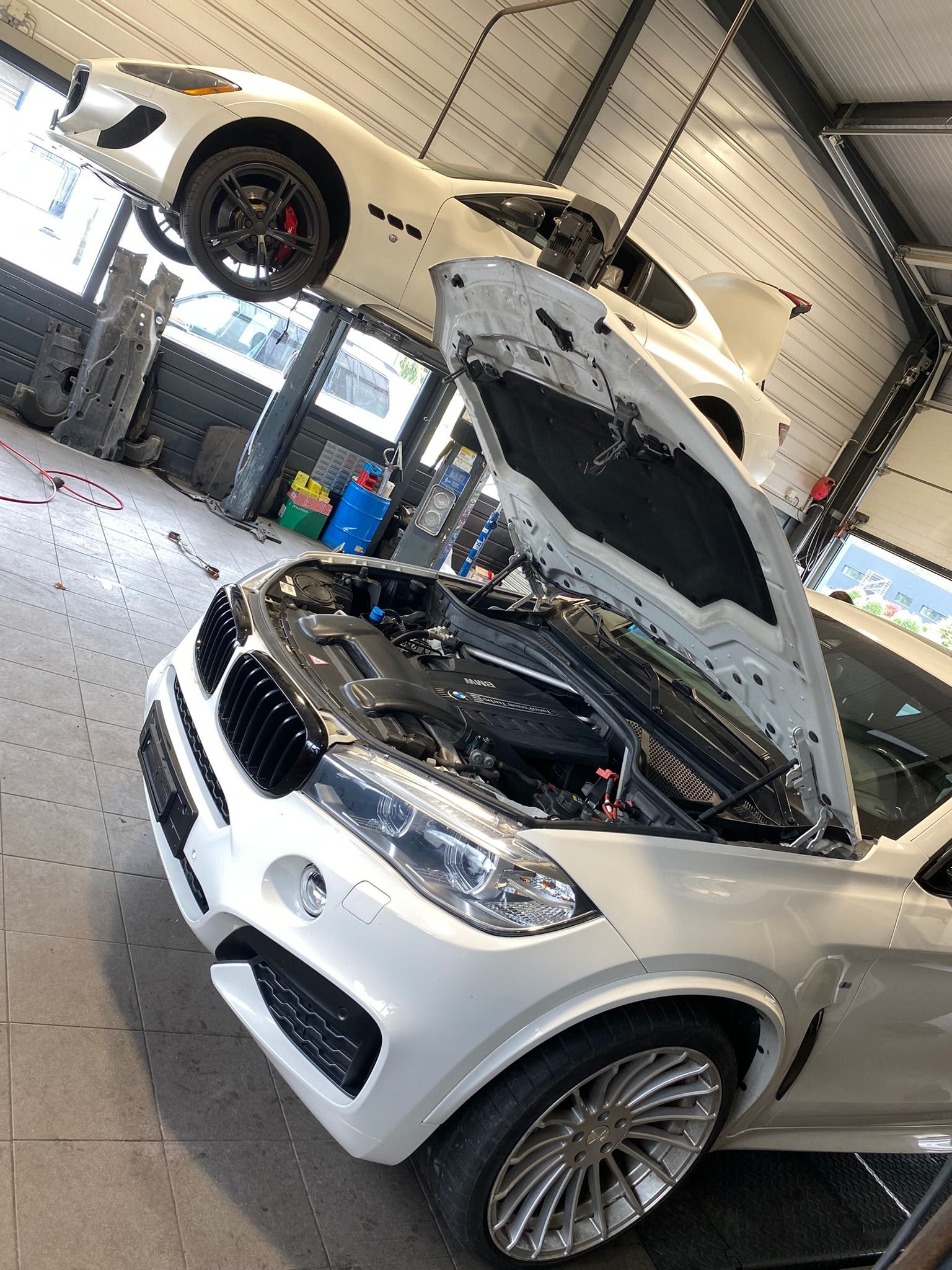 Une voiture blanche avec le capot ouvert dans un garage.