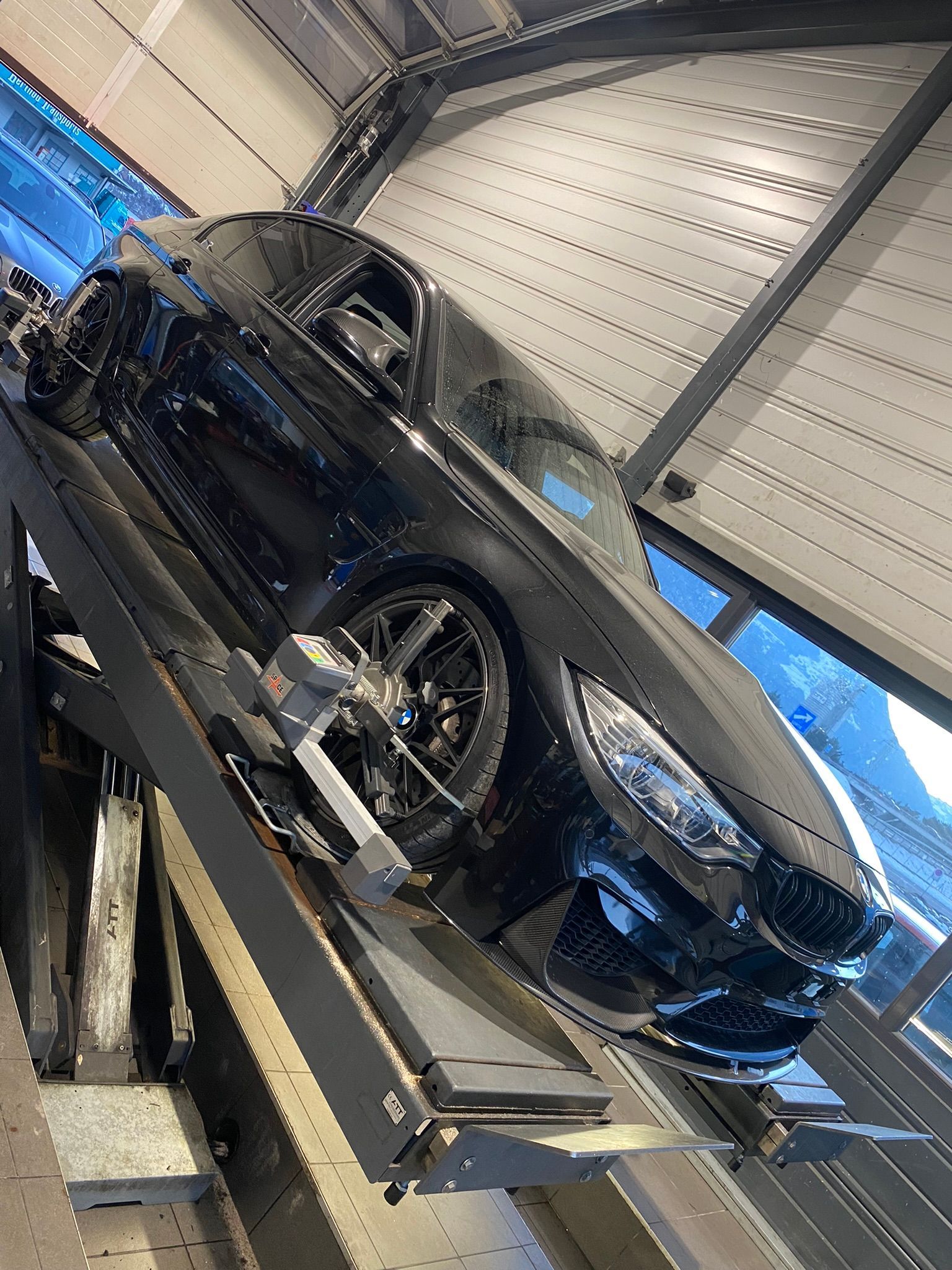 Une voiture noire est assise au sommet d’un ascenseur dans un garage.