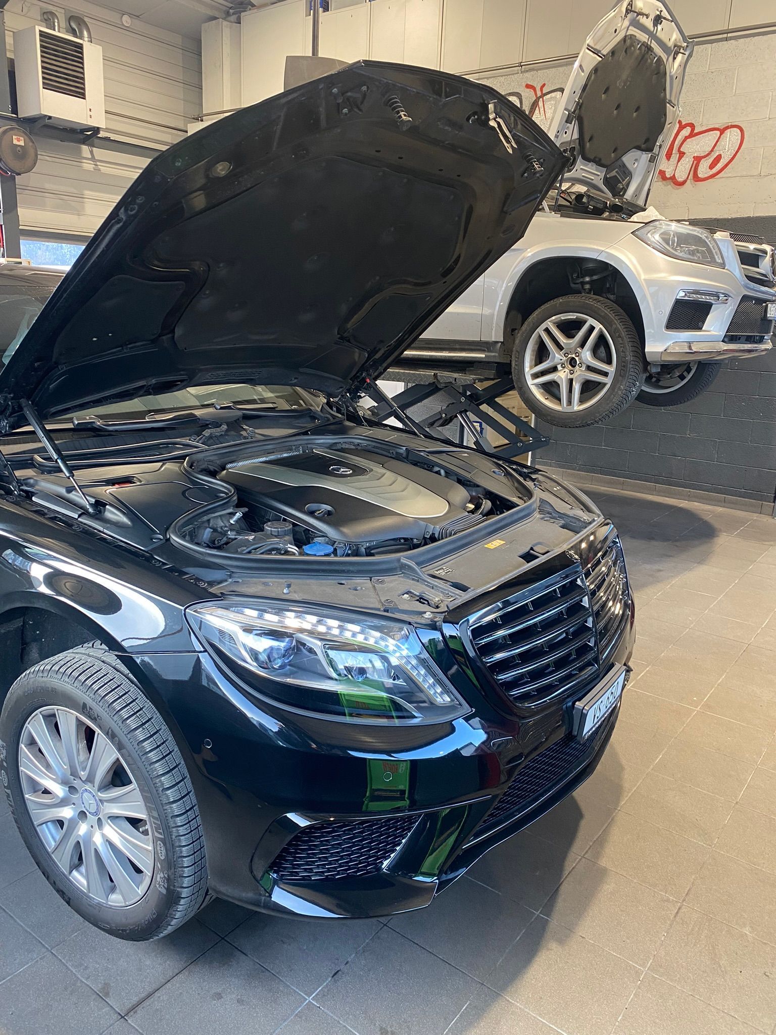 Une voiture noire avec le capot ouvert est garée dans un garage.