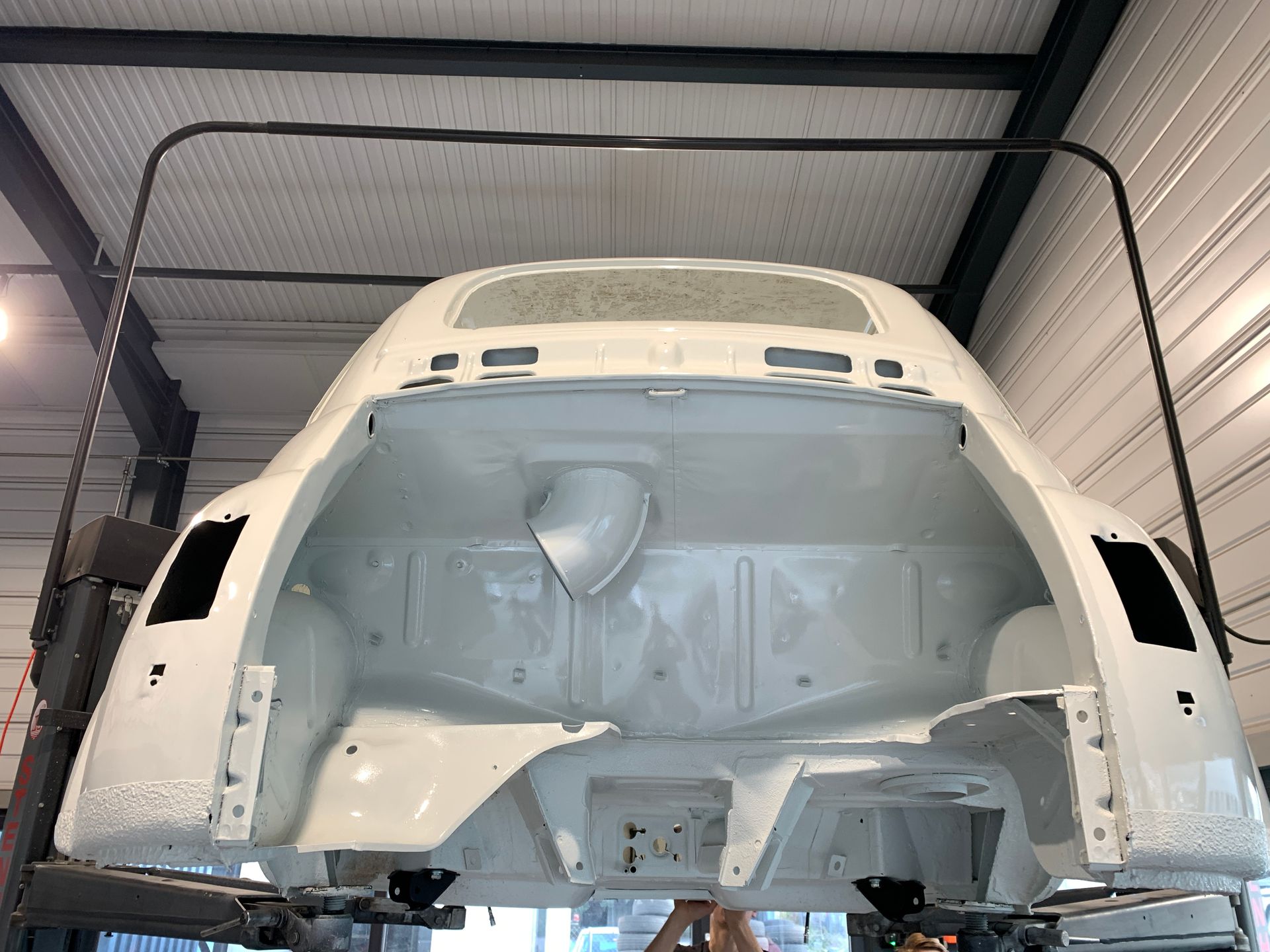 Le coffre d'une voiture blanche est en cours de réparation dans un garage.