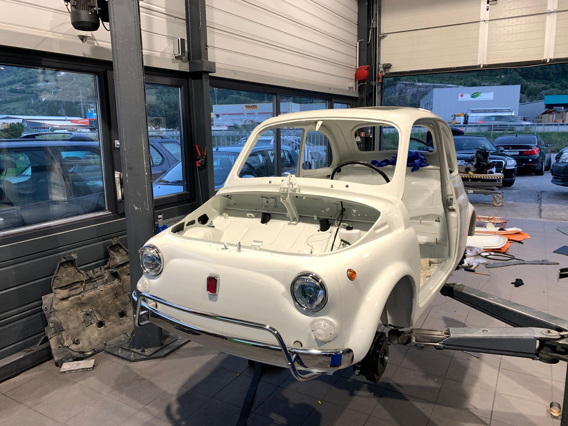 Une voiture blanche est assise sur un ascenseur dans un garage.