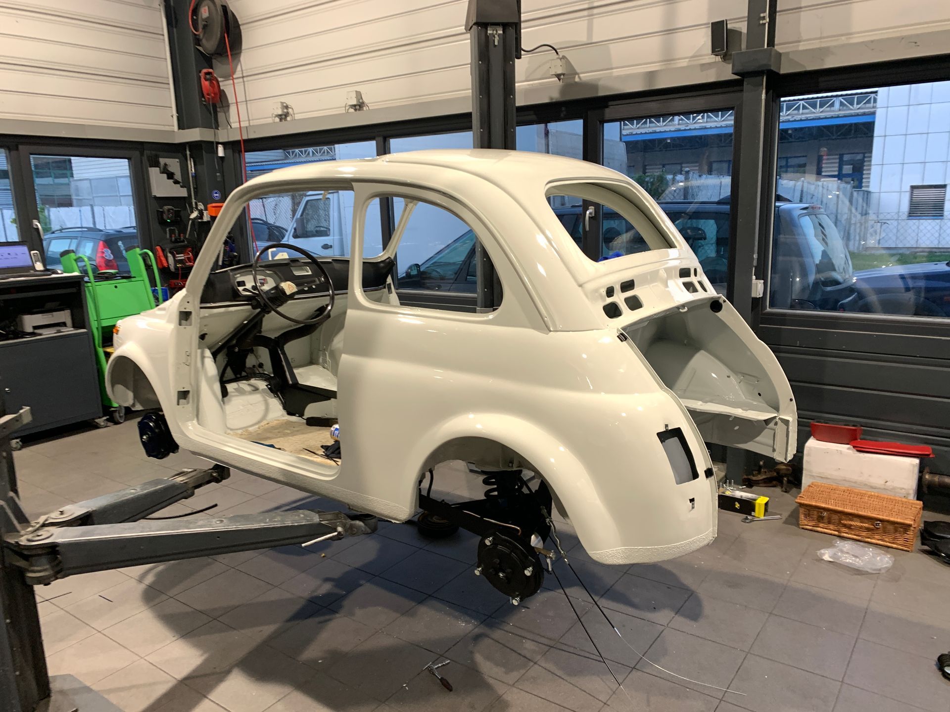 Une voiture blanche est assise sur un ascenseur dans un garage.