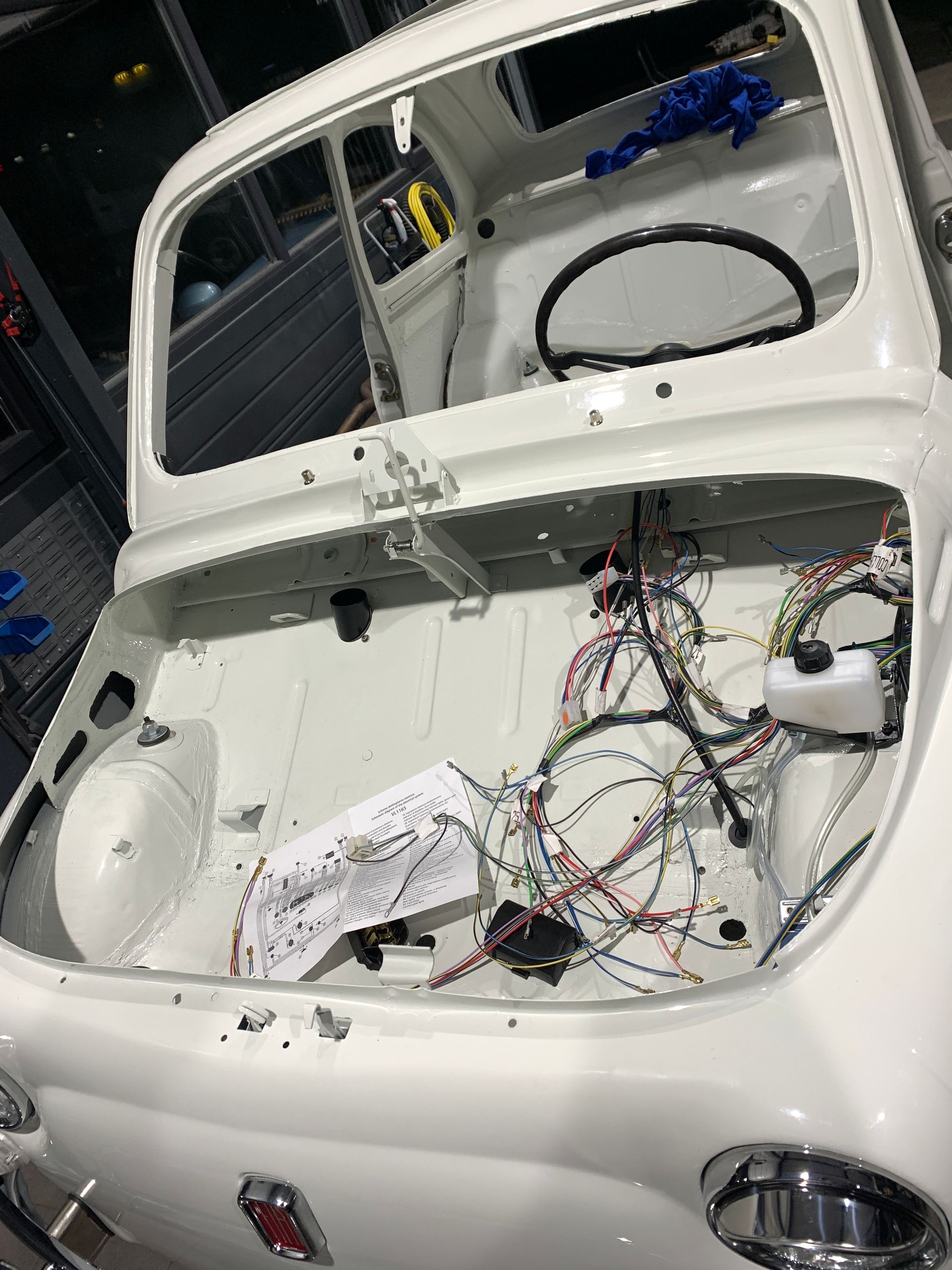 Le coffre d’une voiture blanche avec beaucoup de fils qui en sortent.