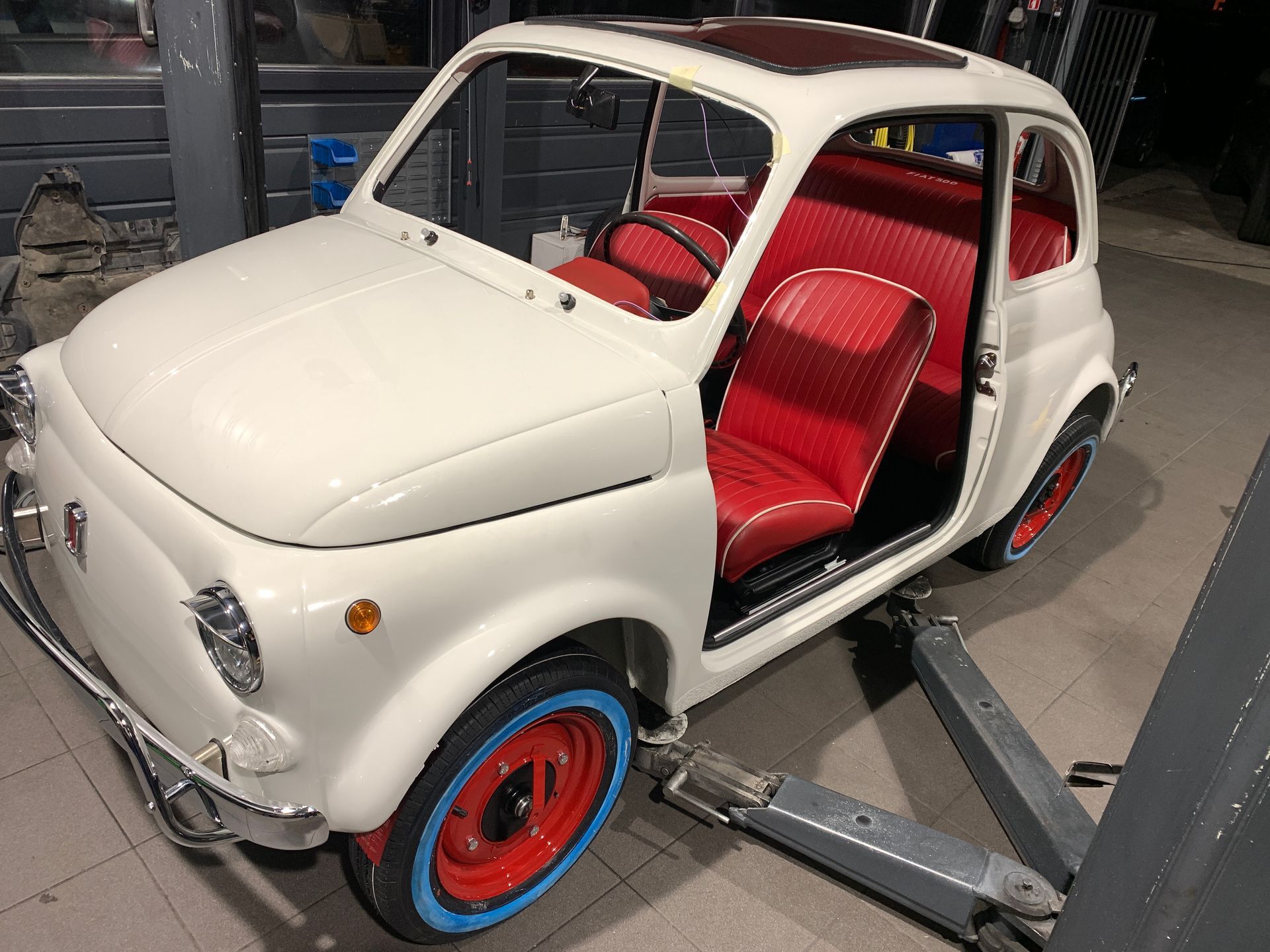 Une voiture blanche aux sièges rouges est assise sur un ascenseur.