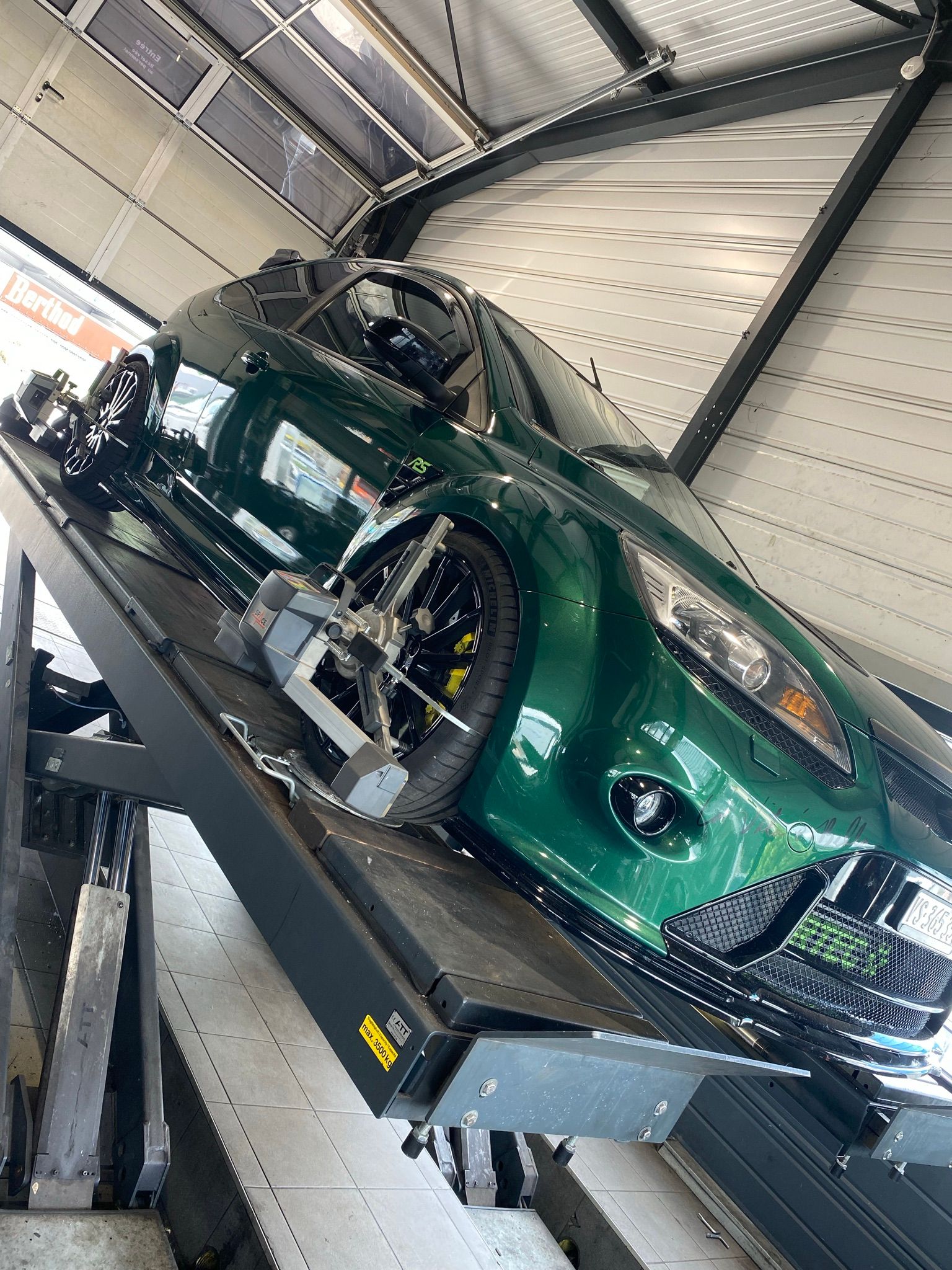 Une voiture verte est assise au sommet d’une dépanneuse.