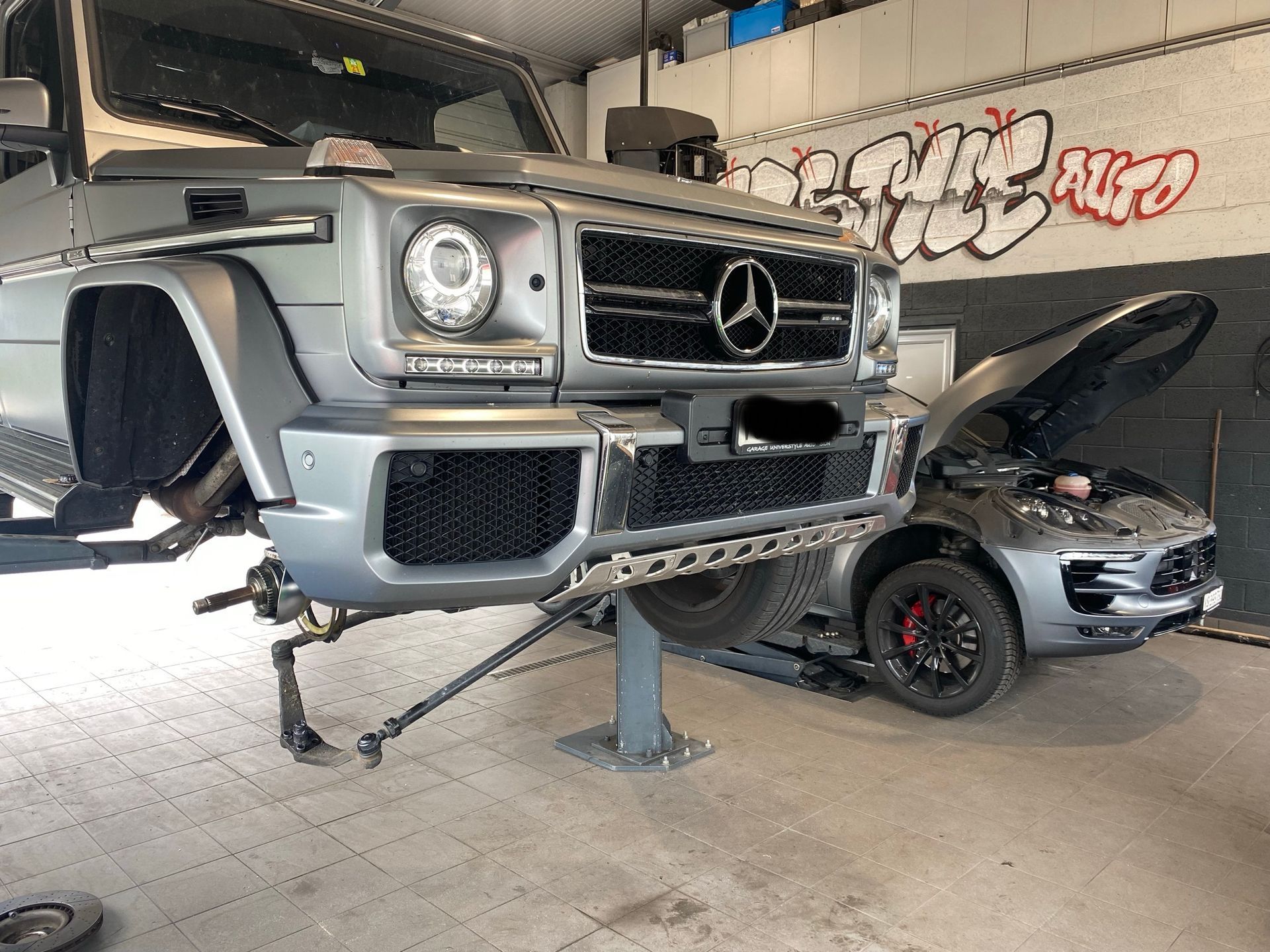 Une Mercedes Benz G63 est assise sur un ascenseur dans un garage.