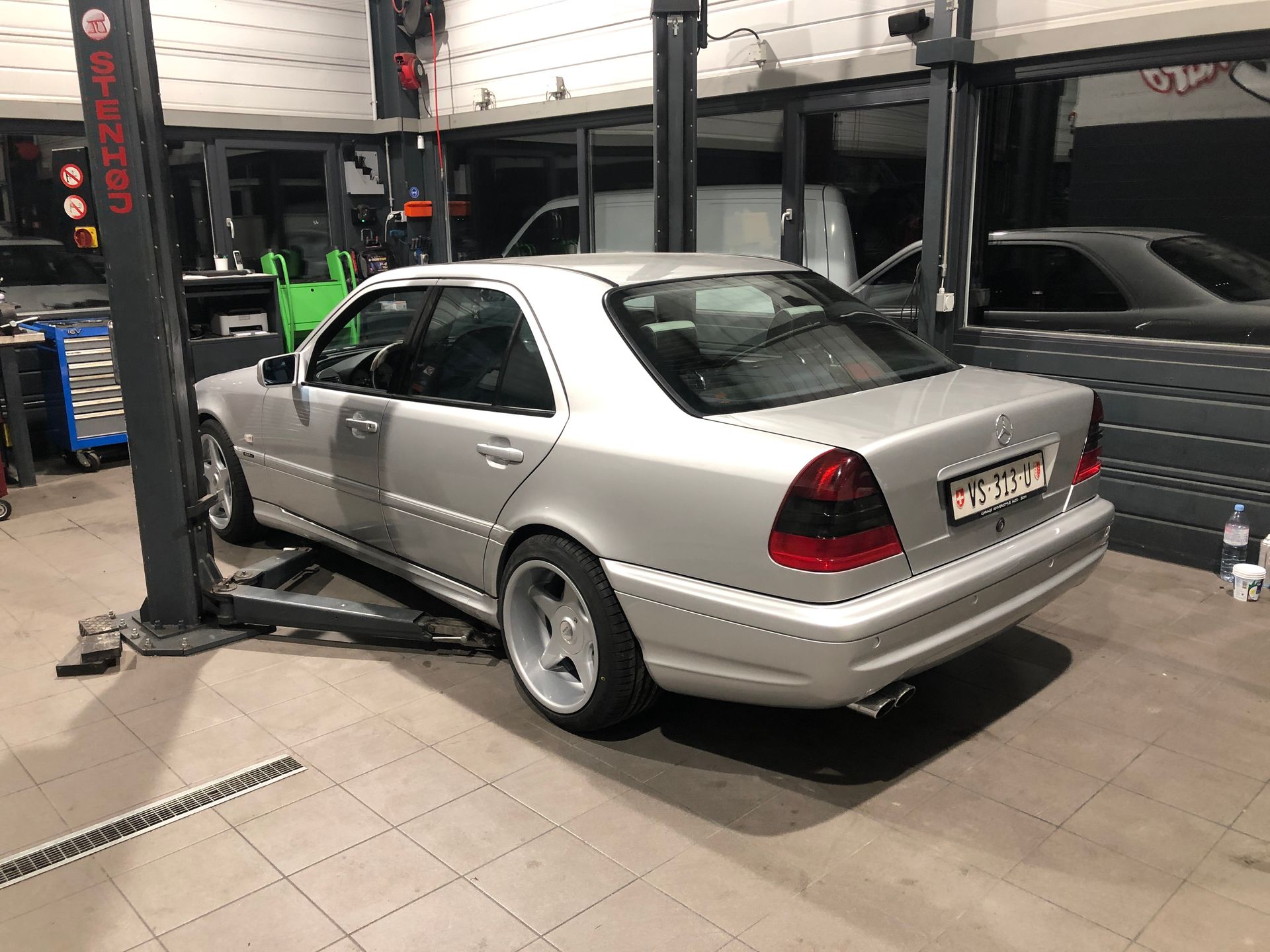 Une voiture argentée est garée sur un ascenseur dans un garage.