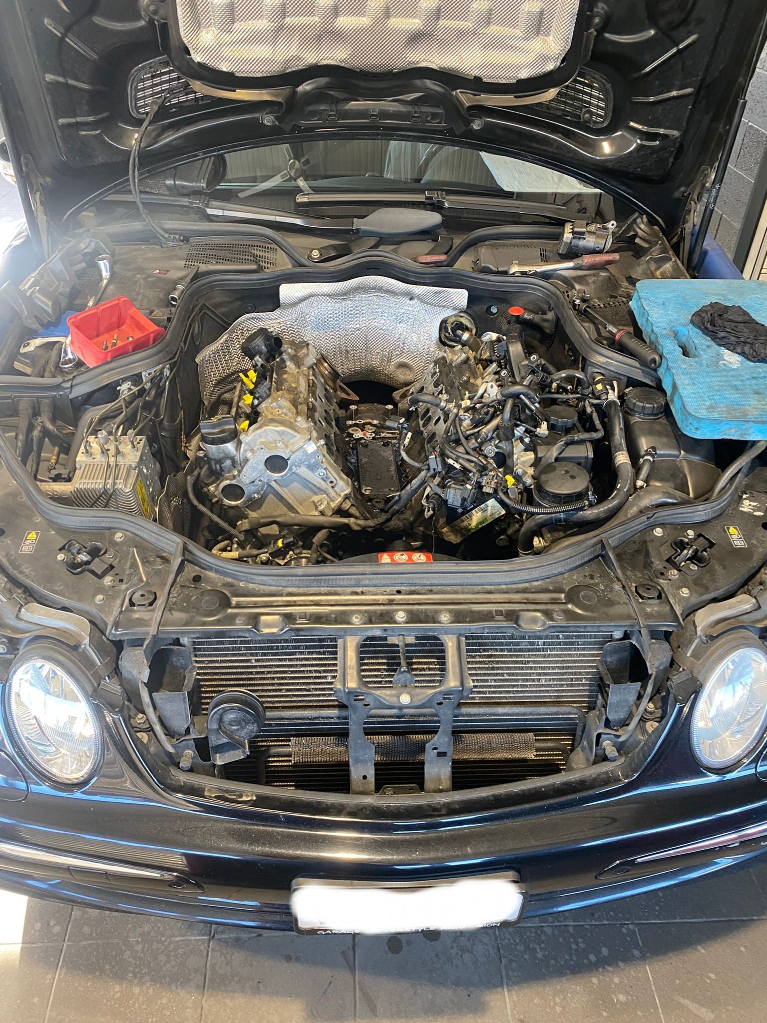 Le capot d'une voiture est ouvert et le moteur est visible.