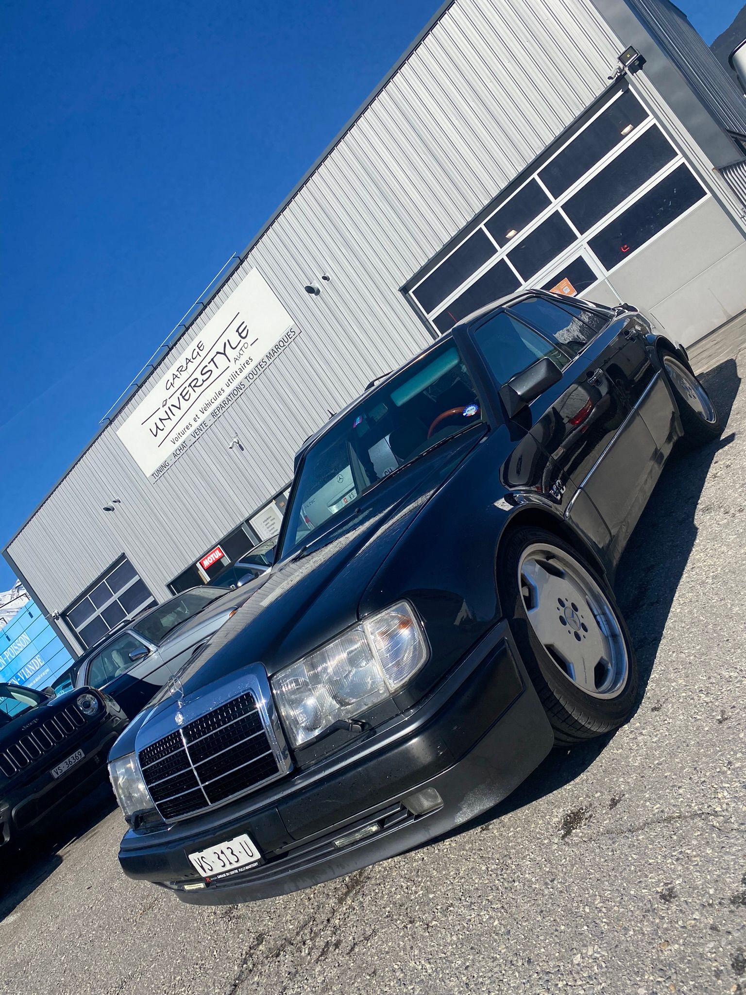 Une Mercedes Benz noire est garée devant un immeuble