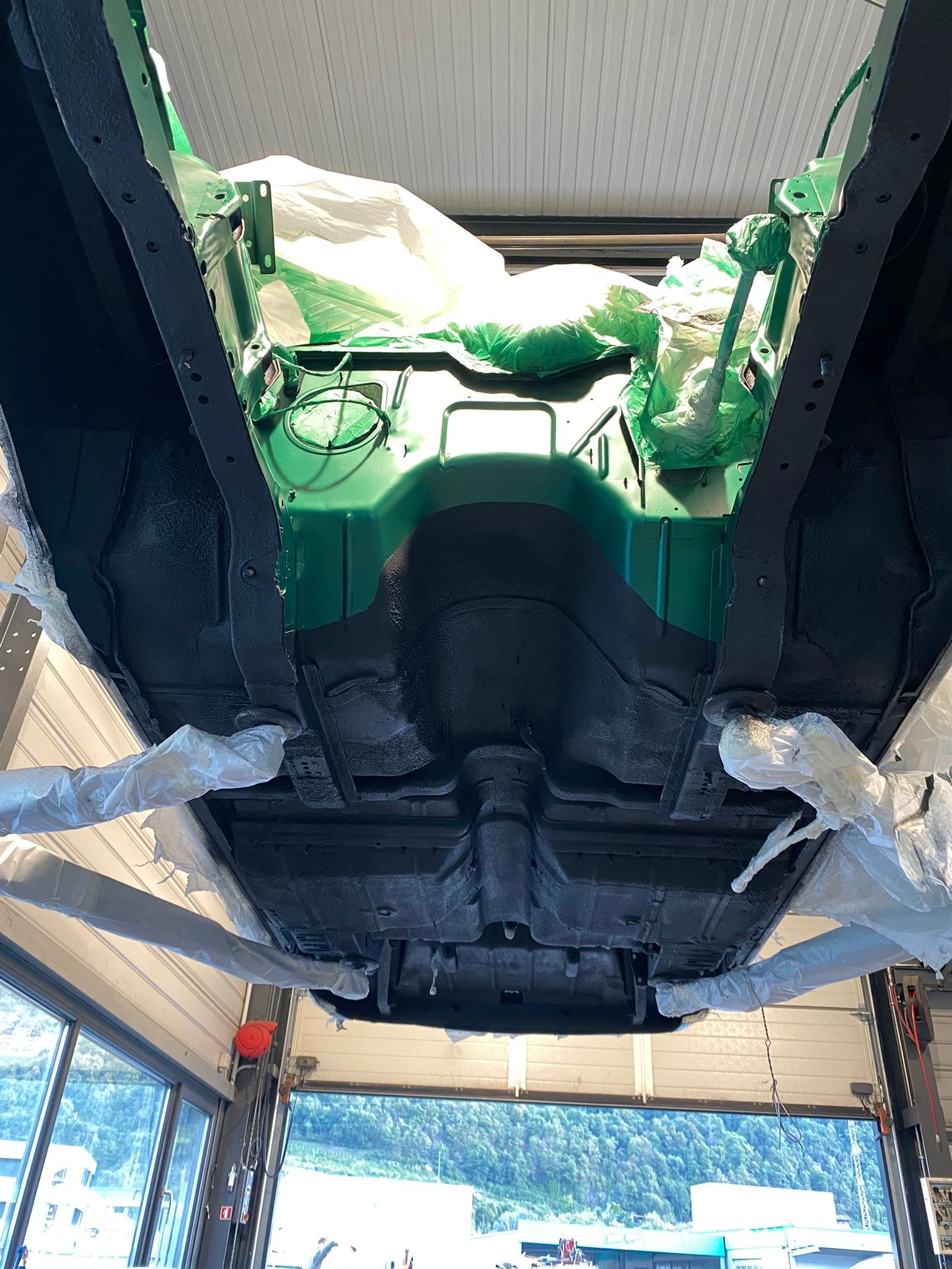 Le bas d’une voiture verte est peint dans un garage.