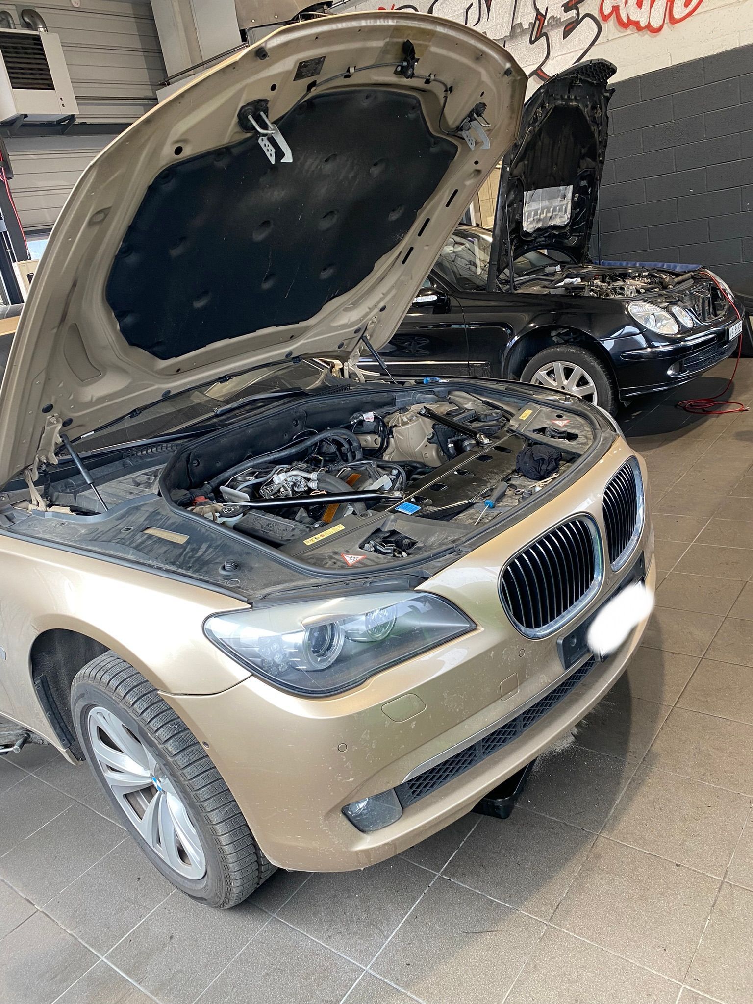 Une voiture avec le capot ouvert est garée dans un garage.
