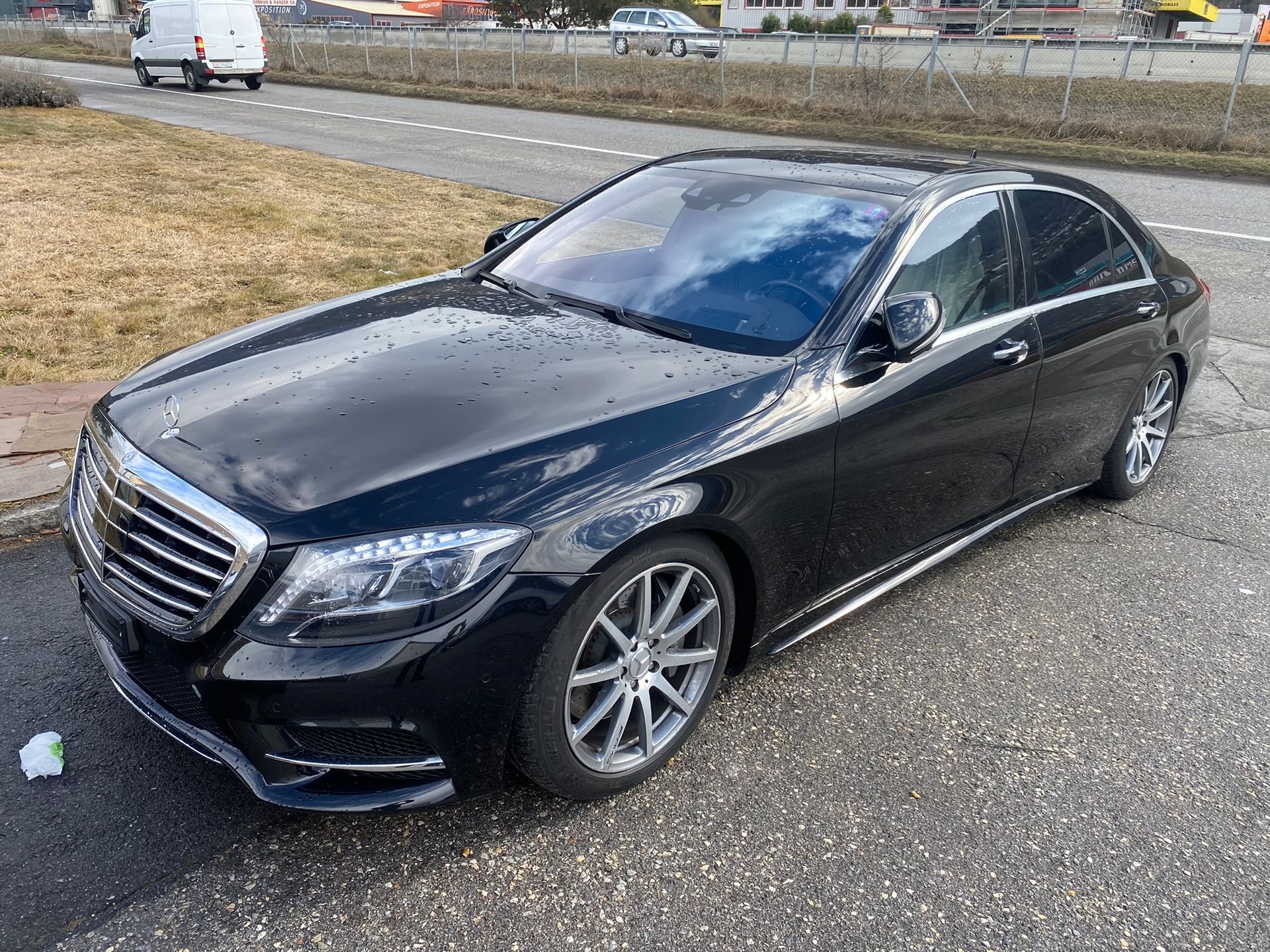 Une classe Mercedes Benz S noire est garée sur le bord de la route.