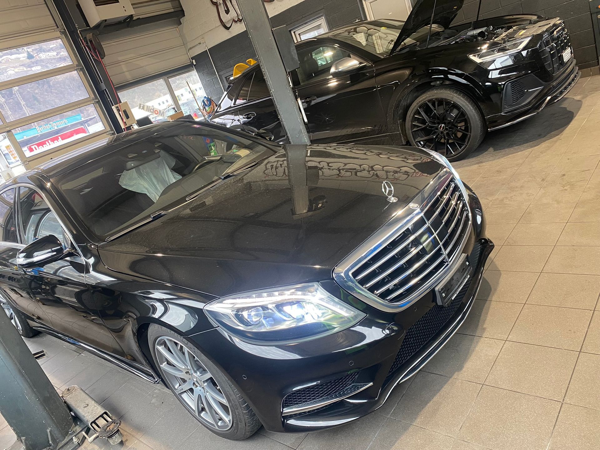 Deux voitures noires sont garées l’une à côté de l’autre dans un garage.