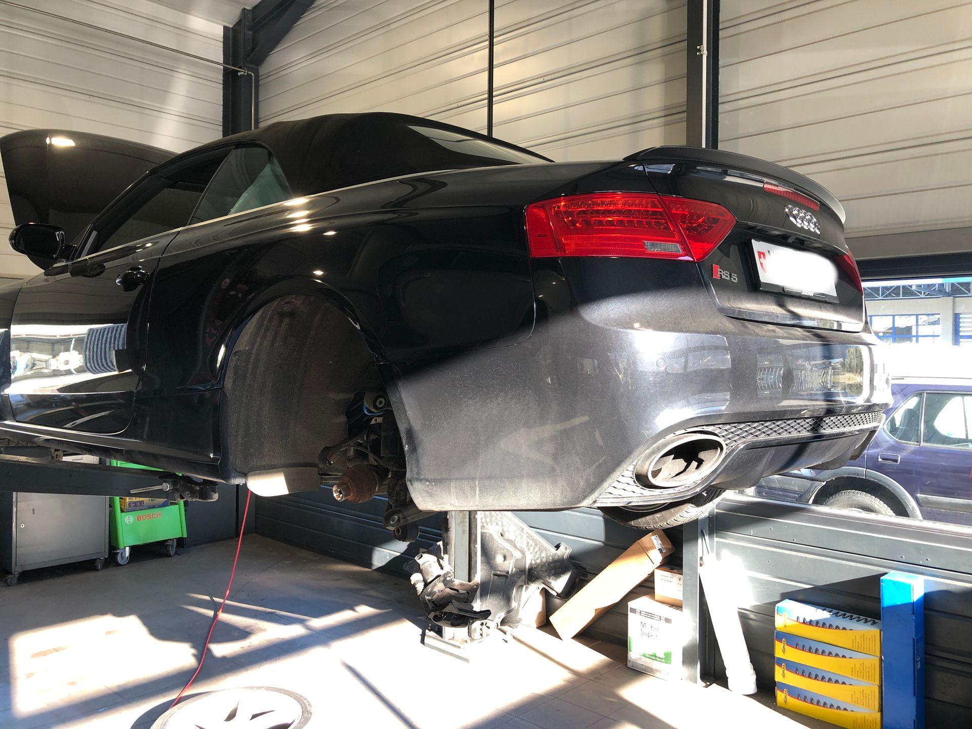 Une voiture noire est assise sur un ascenseur dans un garage.