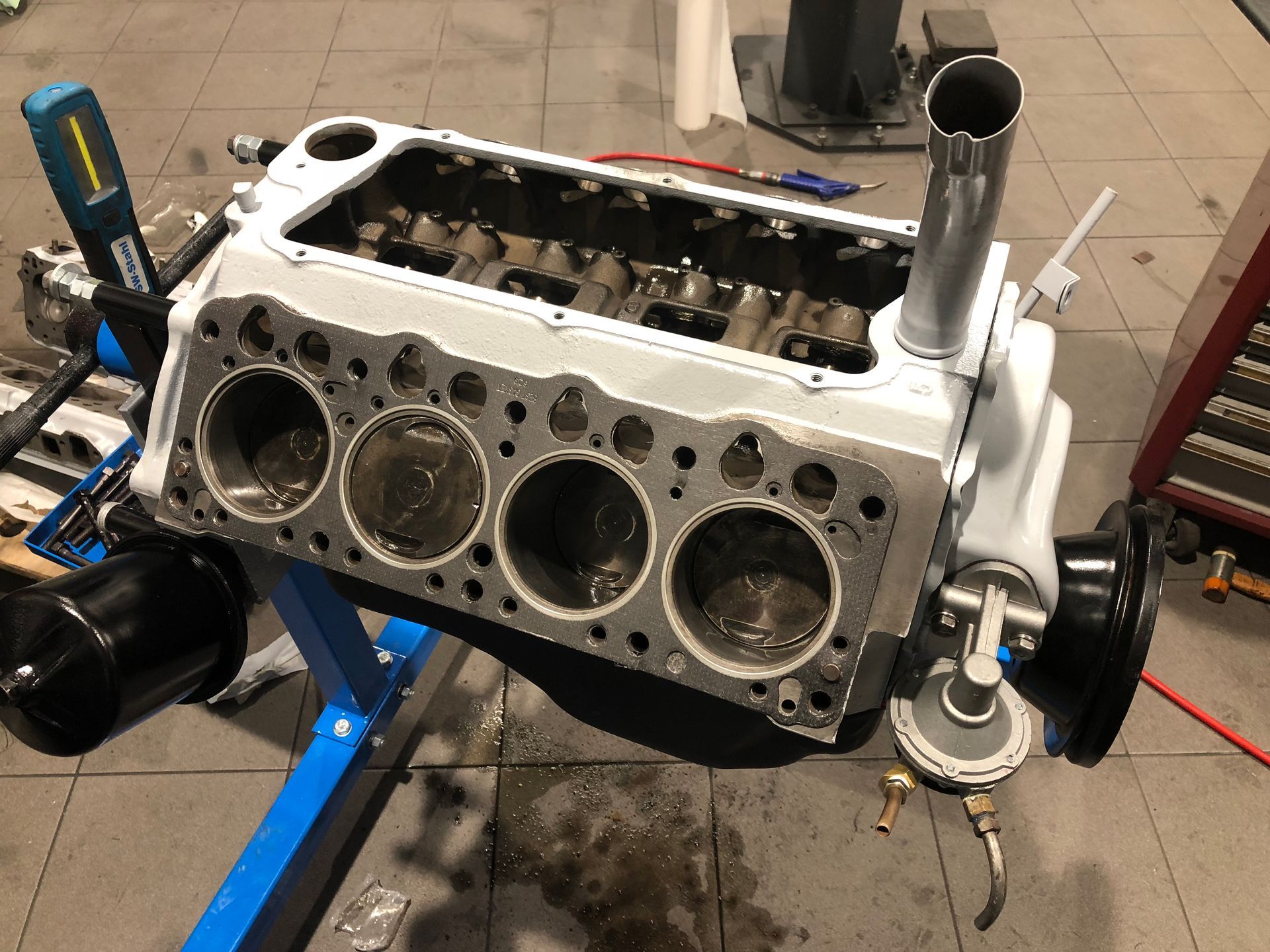 Un moteur de voiture est posé sur un support bleu dans un garage.