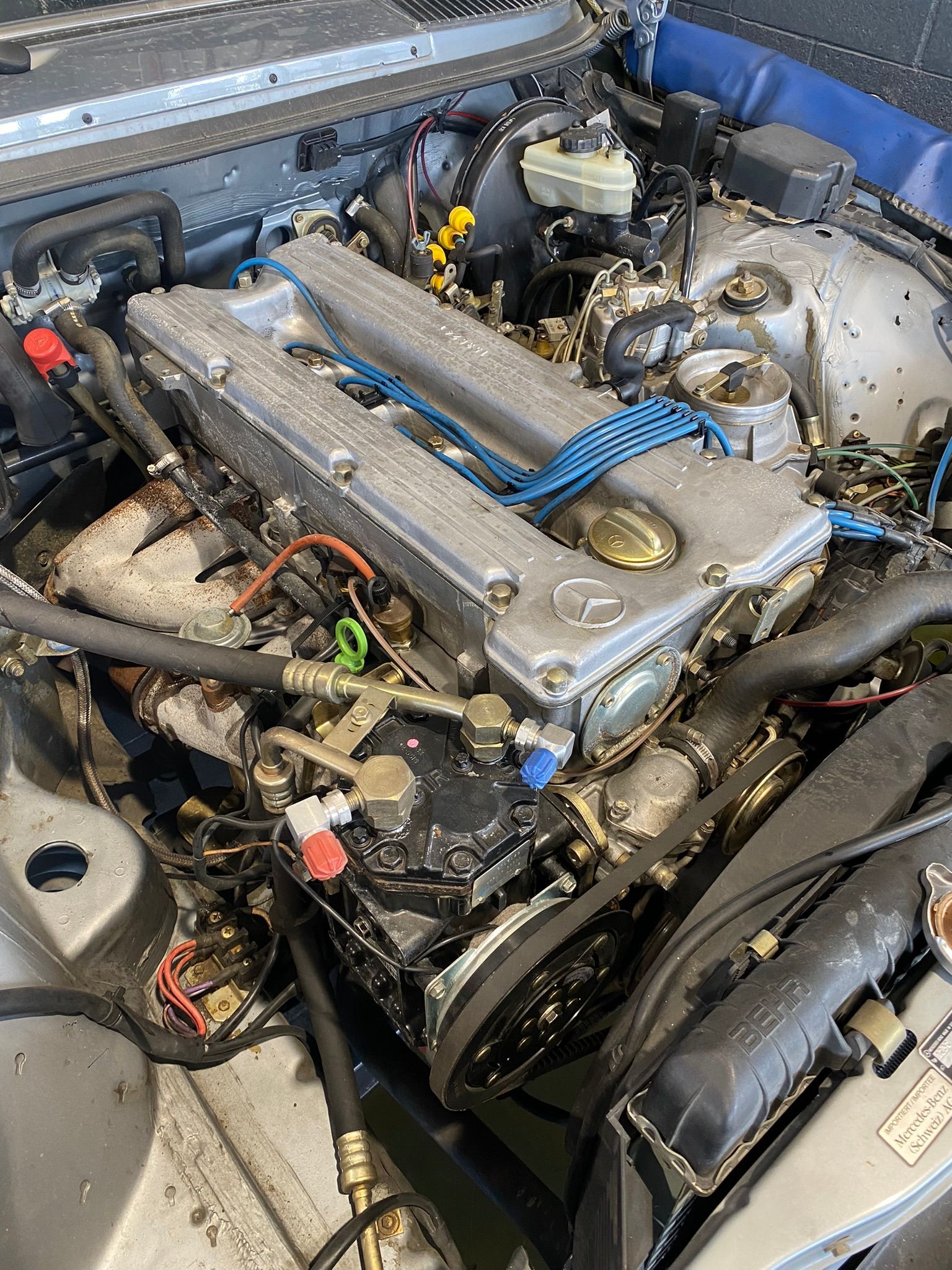 Un gros plan d'un moteur de voiture avec beaucoup de fils qui en sortent.