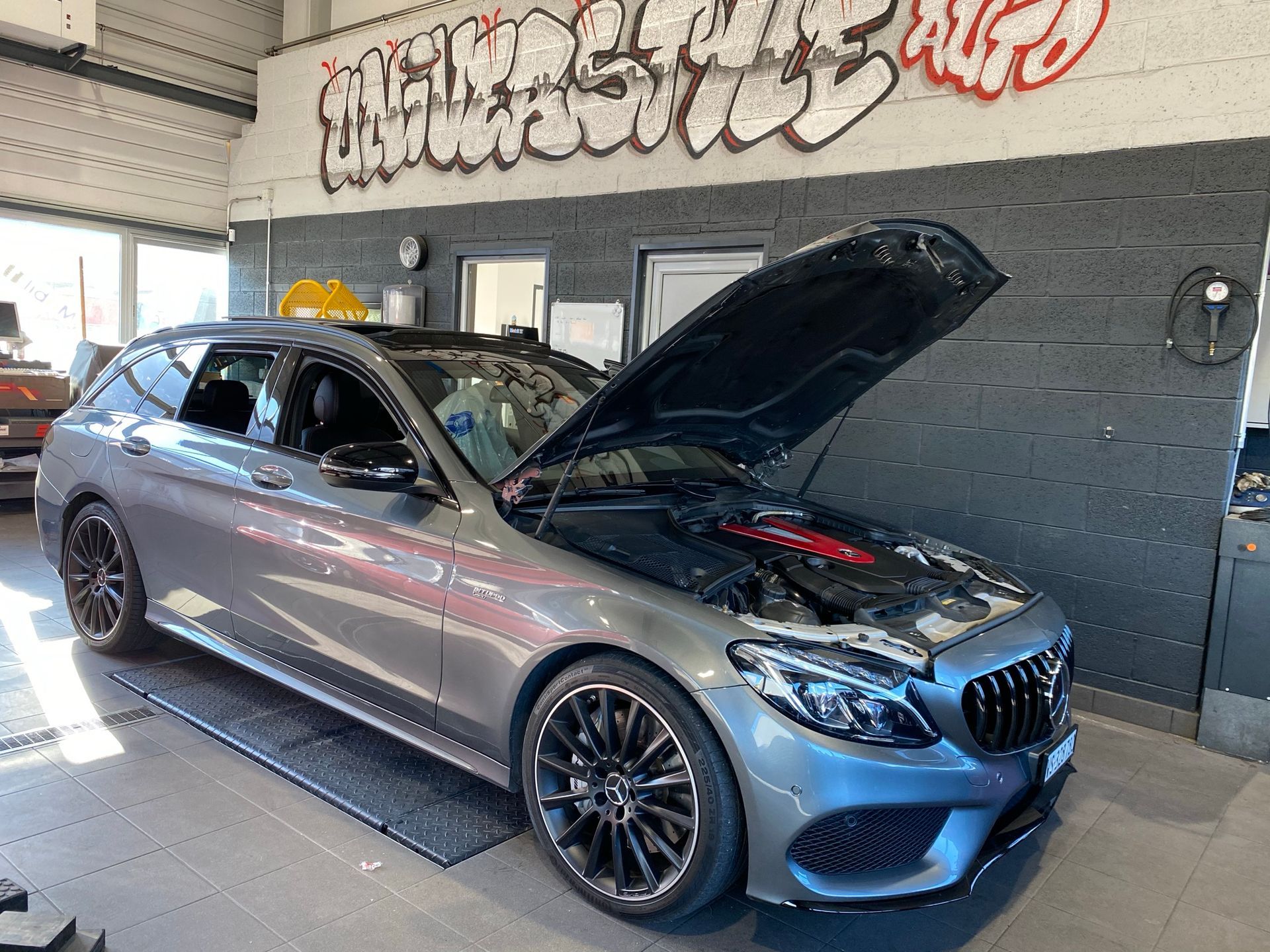 Un break Mercedes Benz Classe C avec le capot relevé dans un garage.