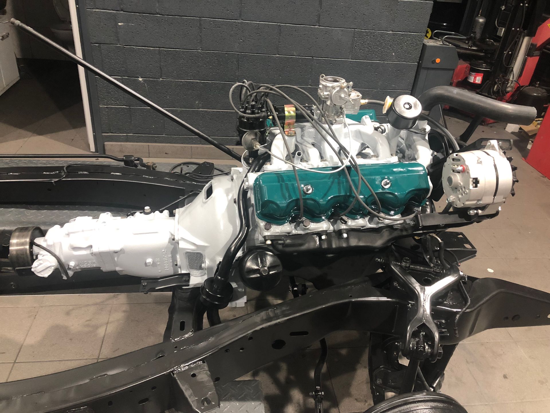 Un moteur de voiture repose sur un châssis dans un garage.