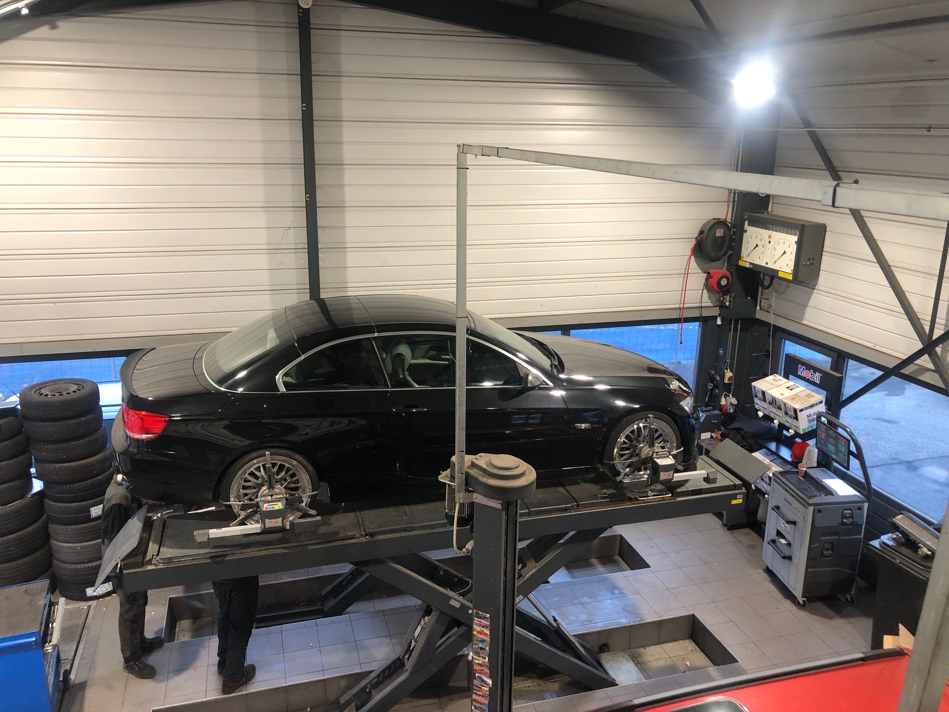 Une voiture noire est assise sur un ascenseur dans un garage.