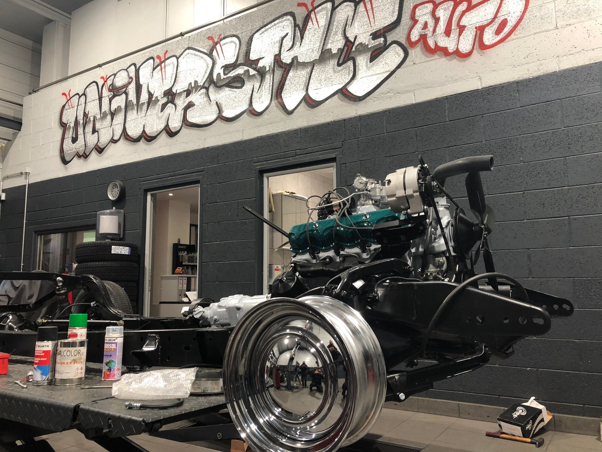 Une voiture est en construction dans un garage avec des graffitis sur le mur.